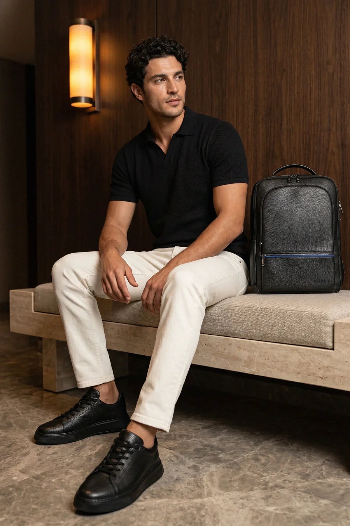 Black leather backpack with blue zipper accents complementing all-black pebbled leather lace up sneakers design