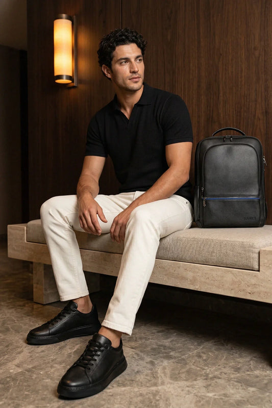 Black leather backpack with blue zipper accents complementing all-black pebbled leather lace up sneakers design