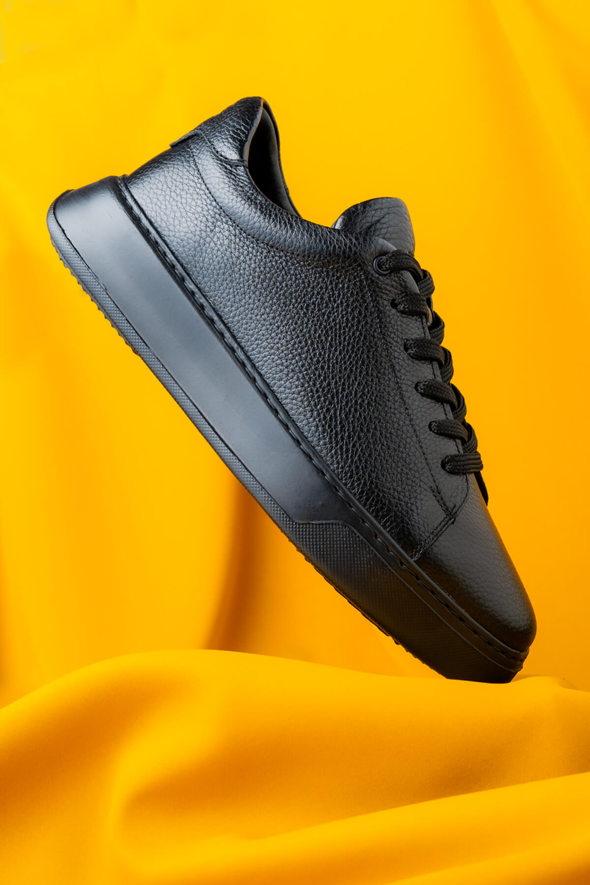 Black leather sneaker with textured upper and matte rubber sole.