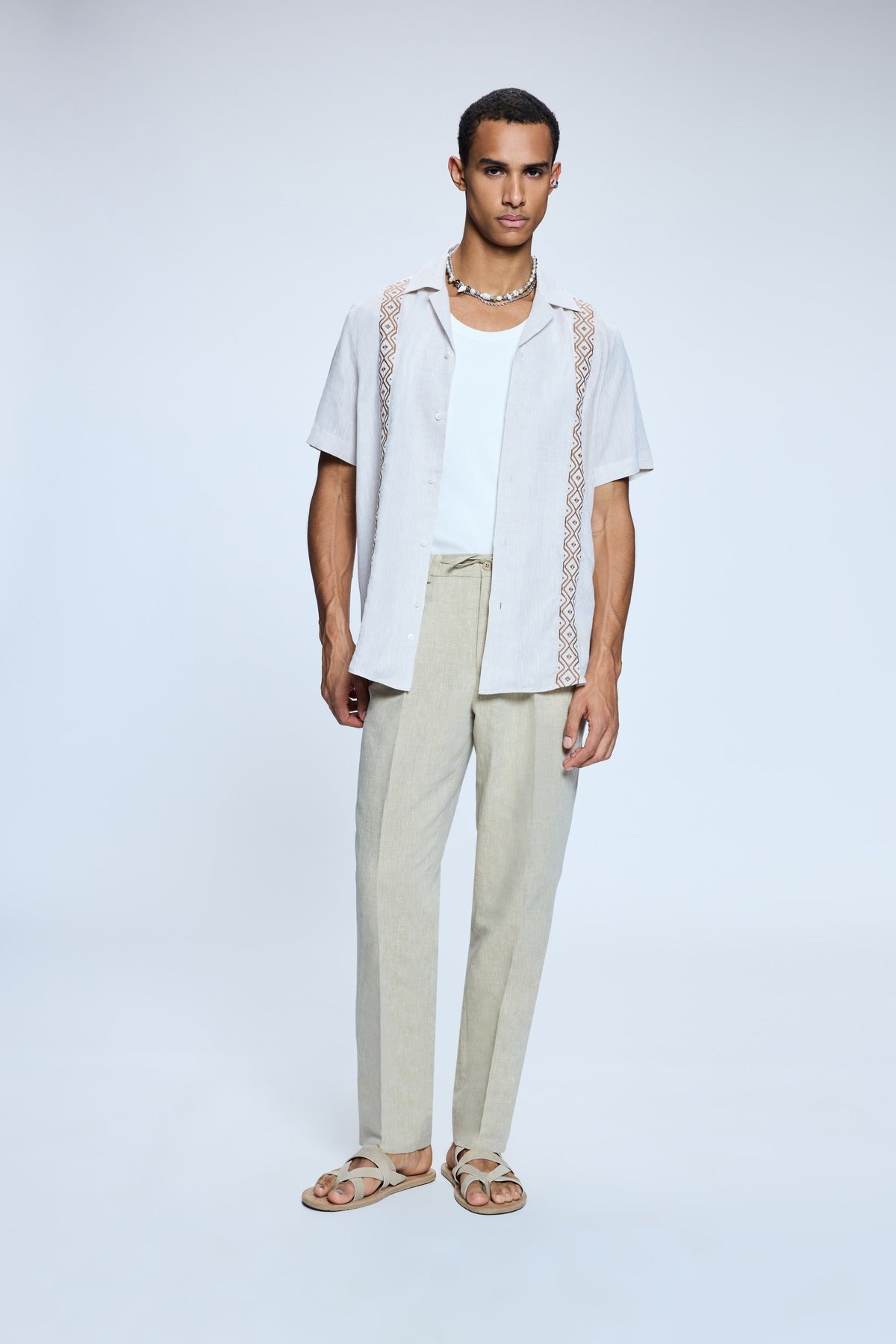 Light gray short-sleeved shirt with intricate geometric embroidery along the collar and sleeve edges