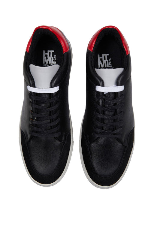 Black leather sneakers with red accents on the heel and white laces, featuring a clean, minimalist design.