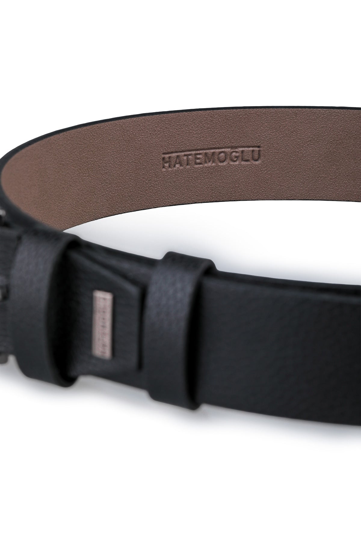 Black leather belt with a minimalist buckle and embossed ’hatemoglu’ branding on the inner lining.