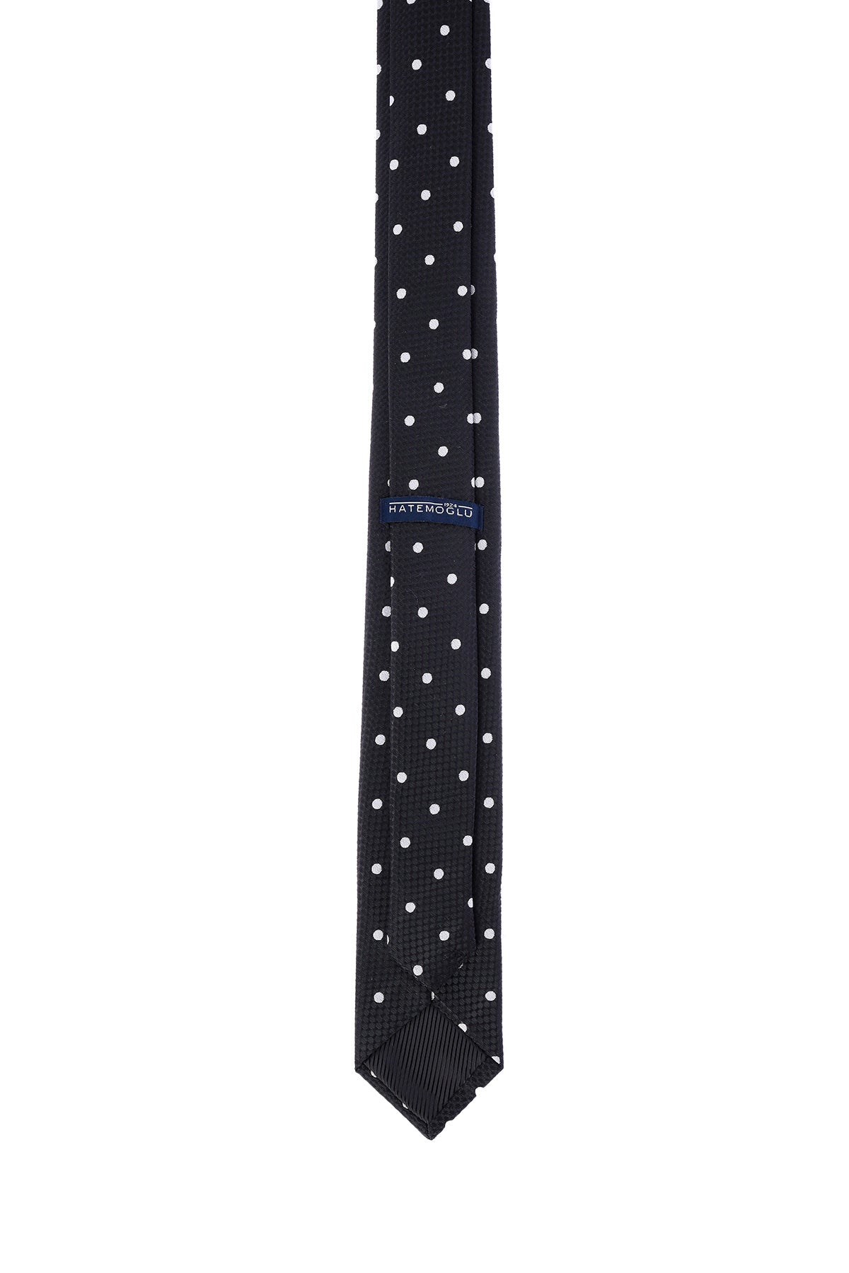 Black tie with white polka dots, featuring a subtle textured weave and a branded label at the center.