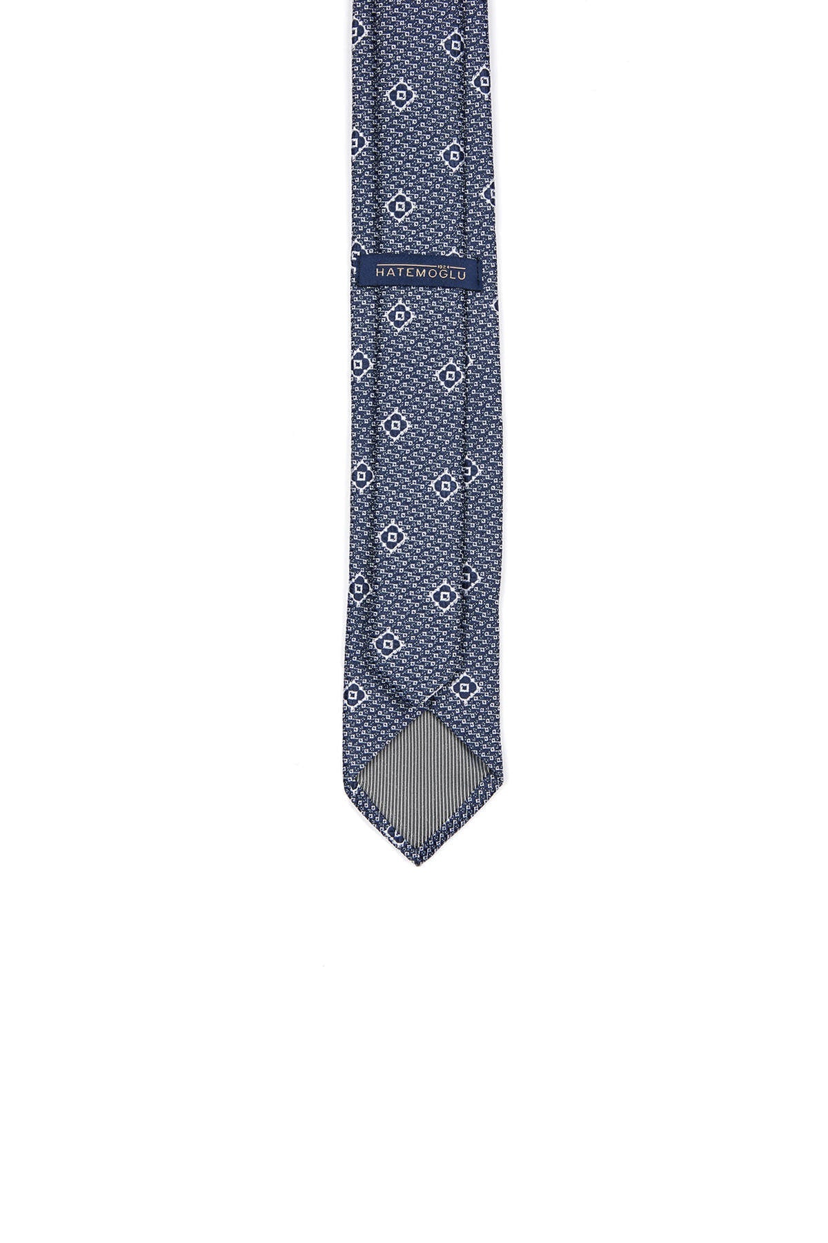 A navy blue silk tie with a subtle geometric pattern of white and light gray diamonds, featuring the hatemoglu brand label.