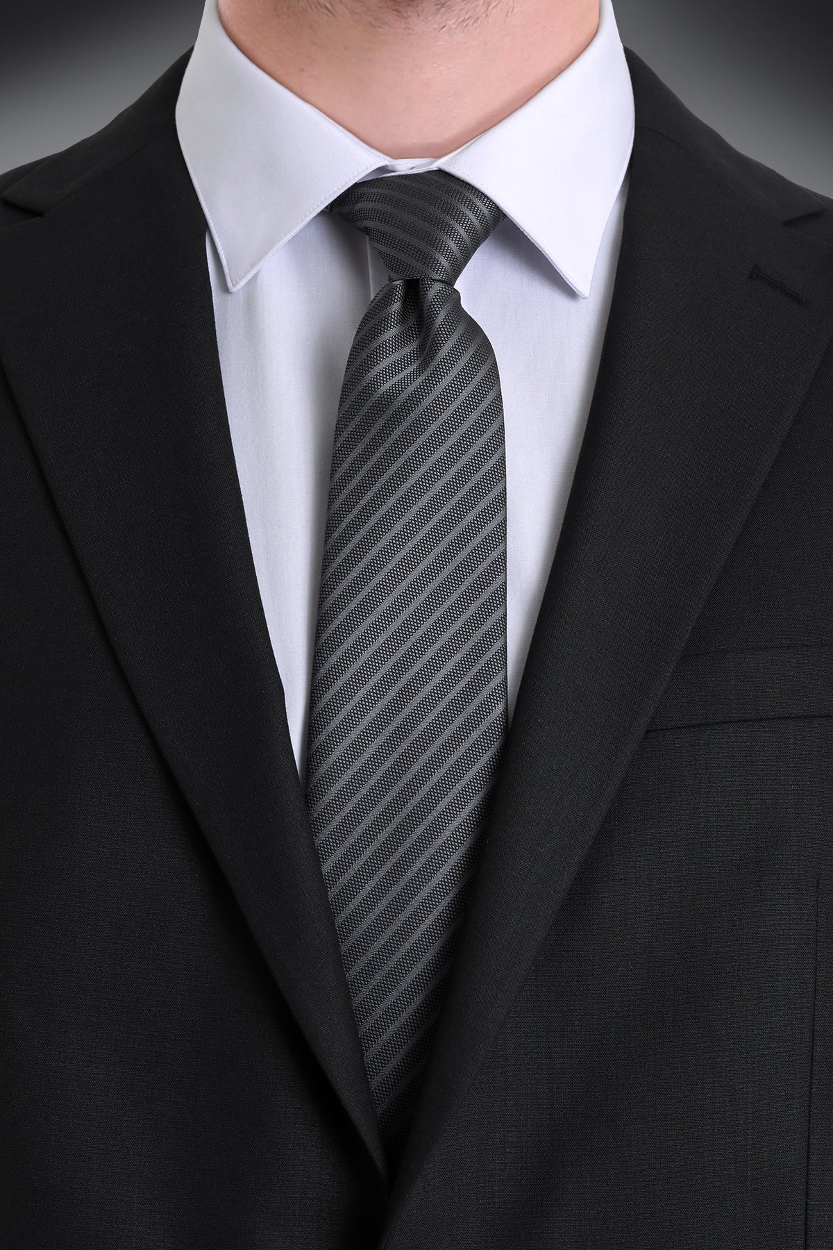 A sleek black tie with subtle diagonal gray stripes, crafted from a smooth, textured fabric.