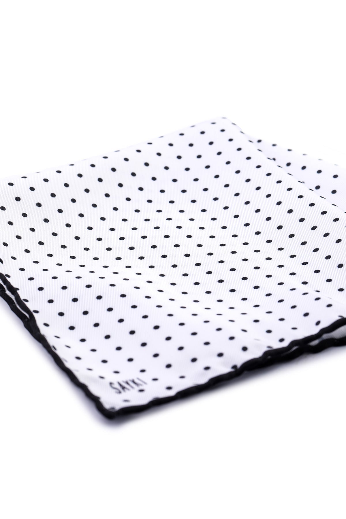 White pocket square with black polka dots and a scalloped edge.