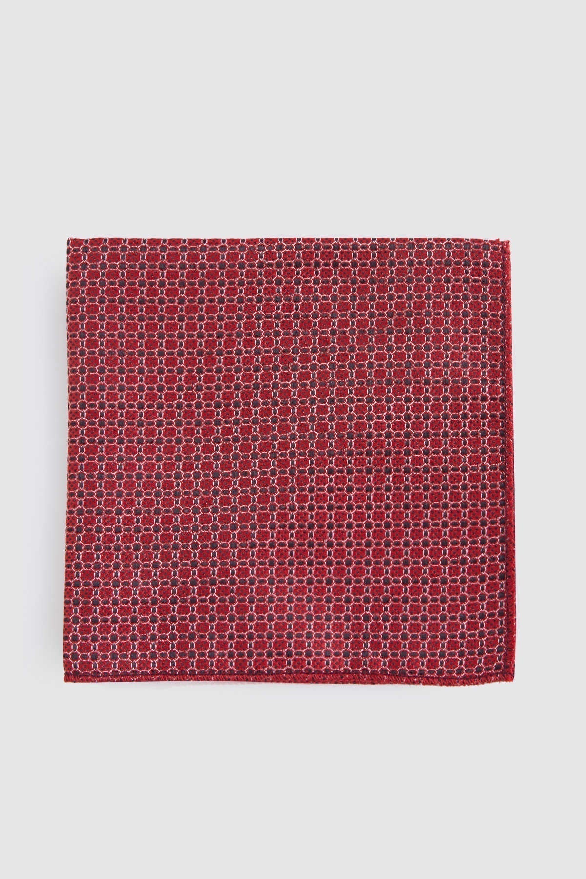 A rich red silk pocket square featuring a subtle geometric pattern of interlocking hexagons in darker tones.