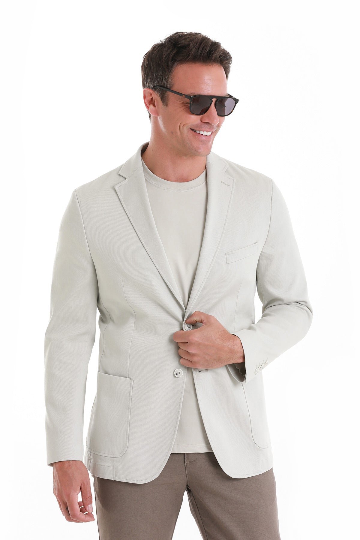 A light beige, single-breasted blazer with a subtle texture and two front flap pockets.