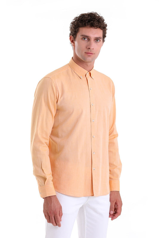 A man wearing a peach-colored, long-sleeved button-down shirt with a classic collar and neatly pressed fabric.
