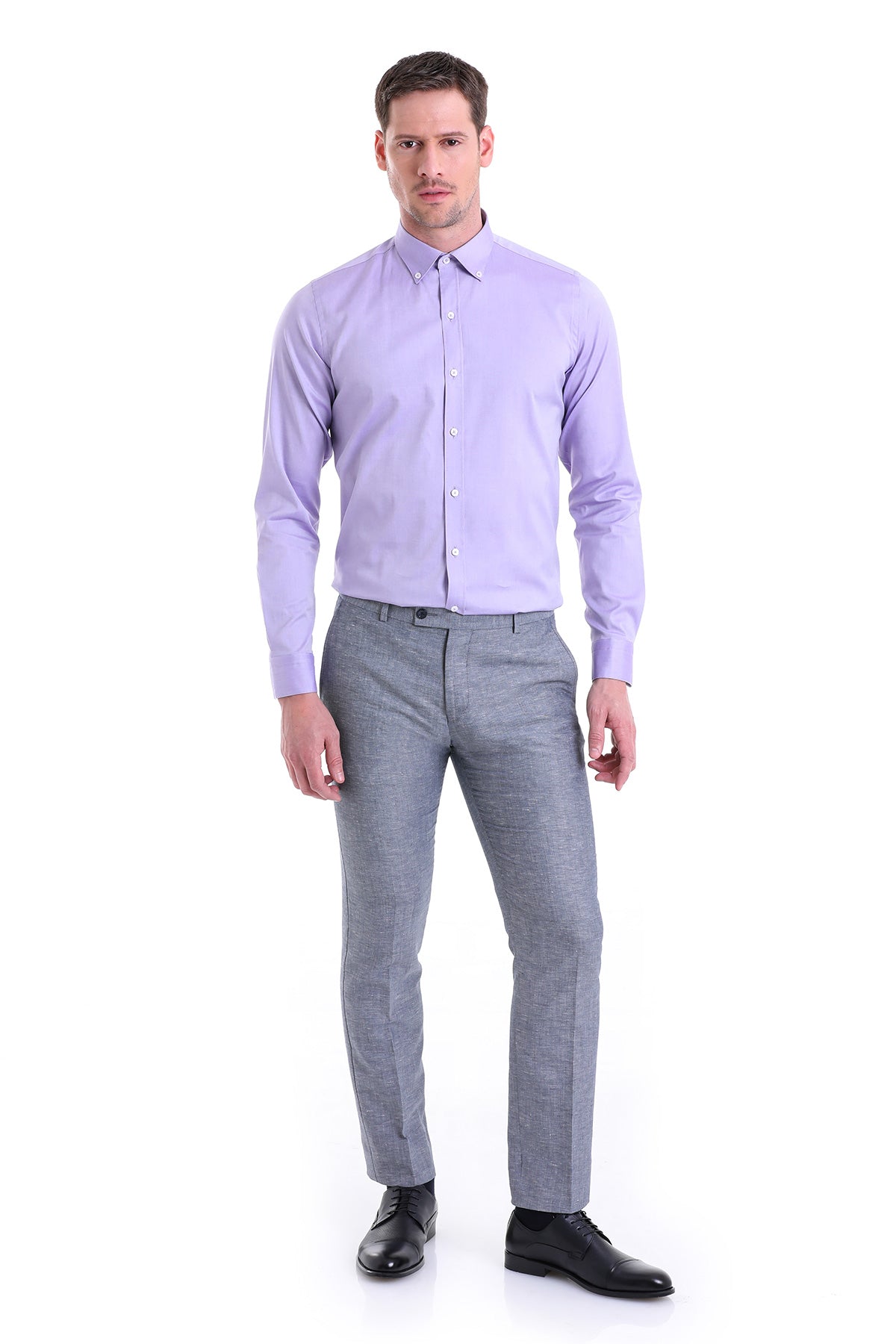 A man wearing a lavender long-sleeved button-down shirt paired with gray textured trousers and black dress shoes.