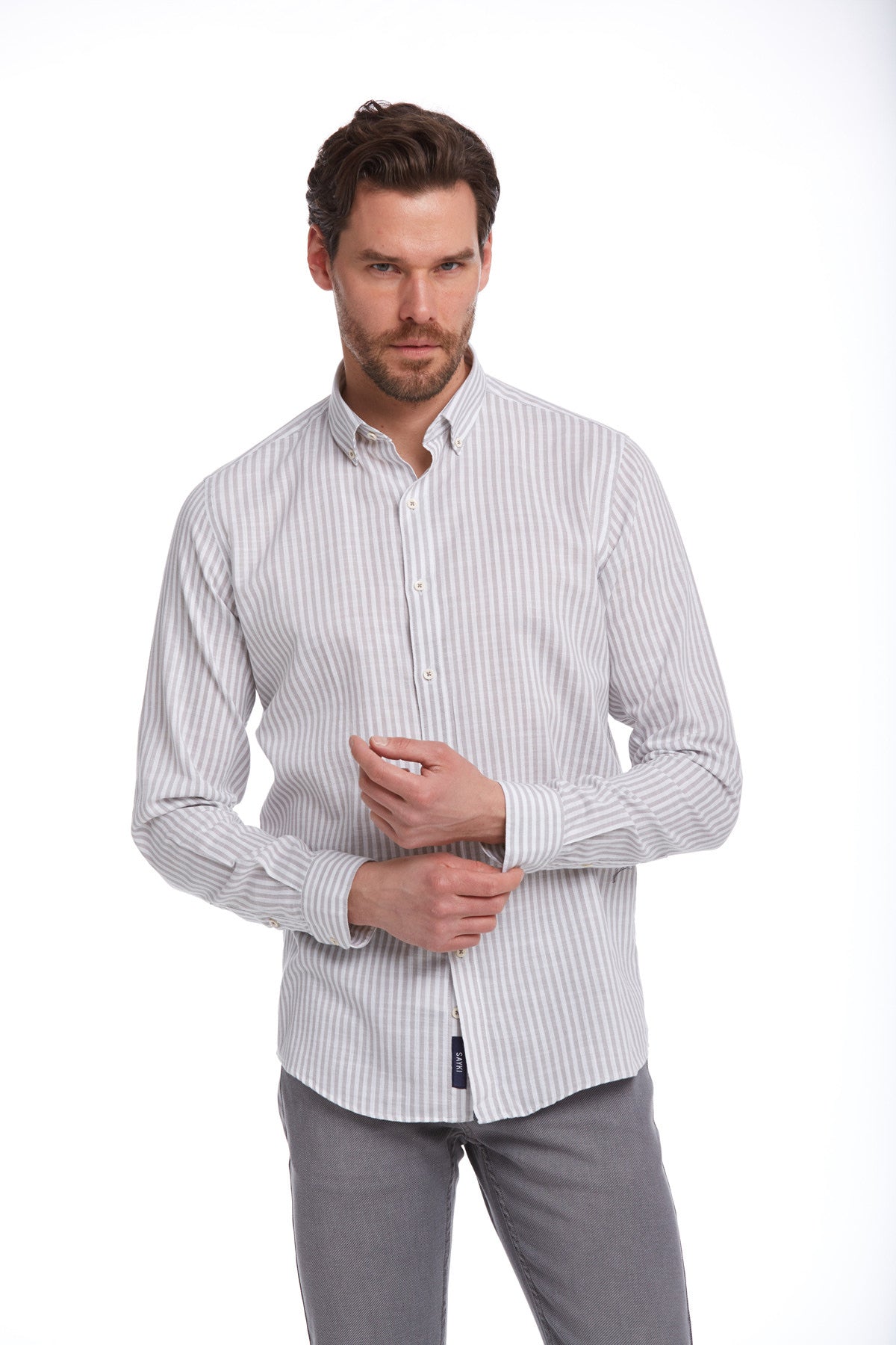 A men’s long-sleeved button-down shirt with fine vertical stripes in light gray and white, made of a smooth cotton blend fabric.
