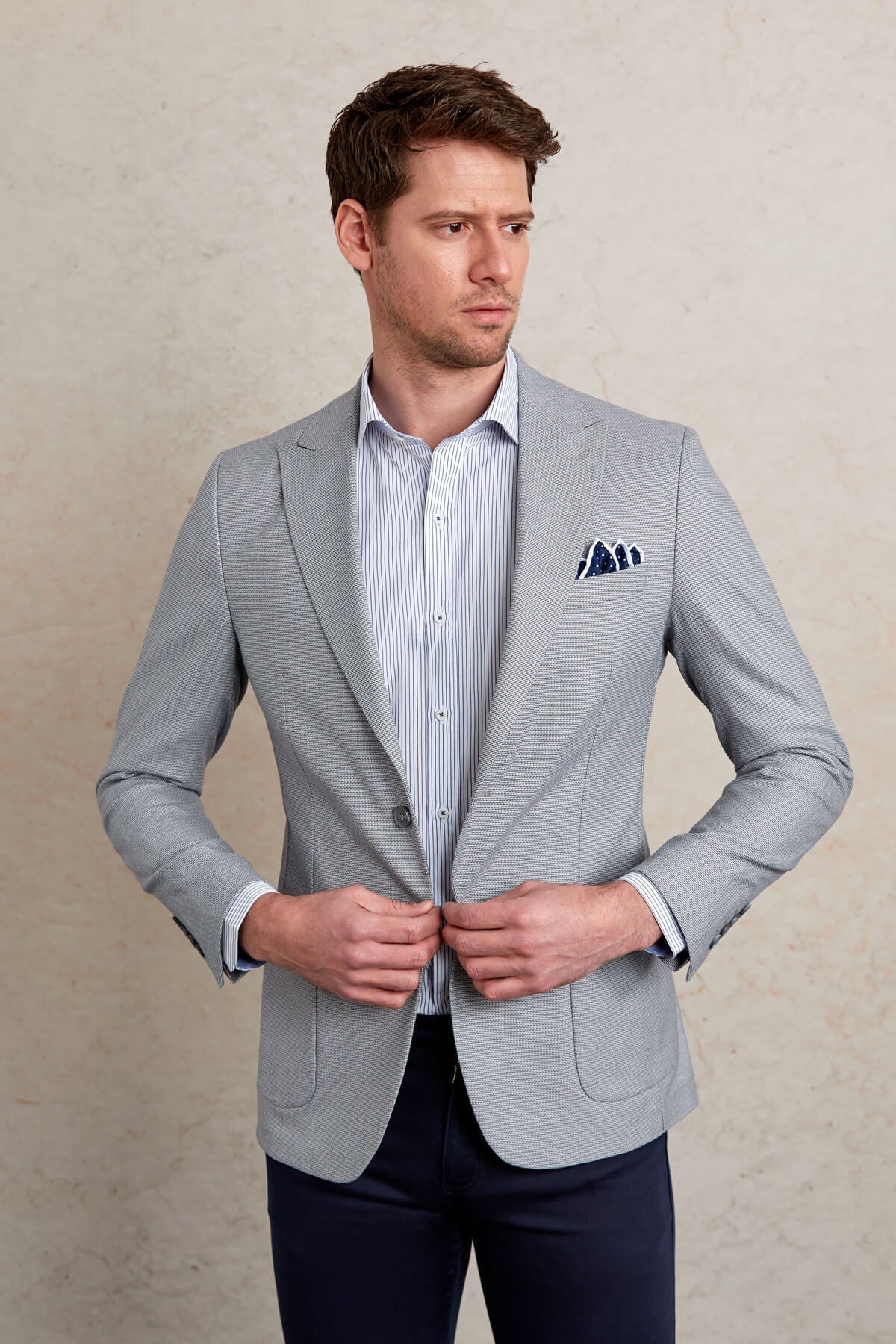 Light gray textured blazer with a subtle herringbone pattern and navy blue pocket square.