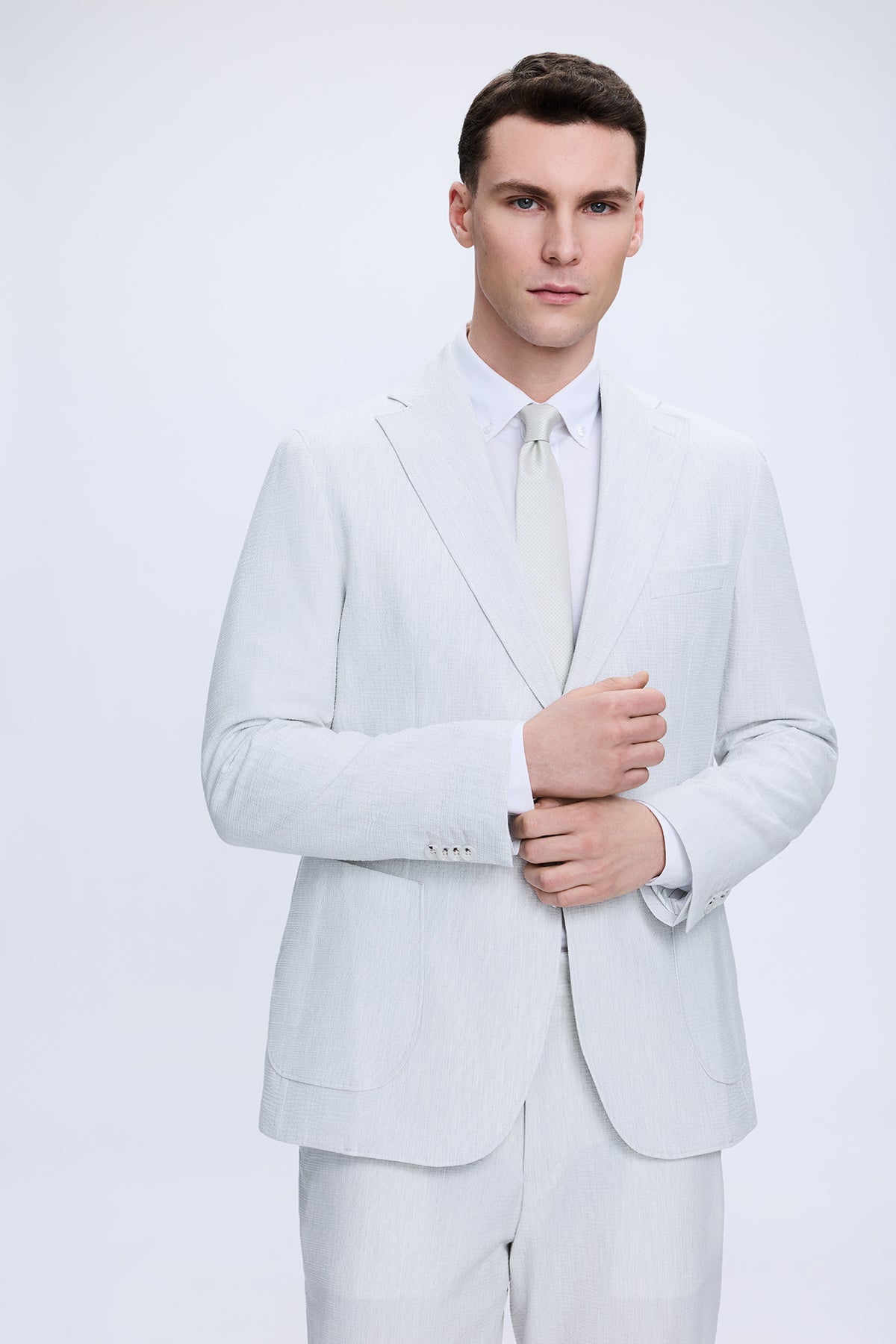 A man wearing a light gray comfort fit striped casual suit with matching trousers and coordinating tie