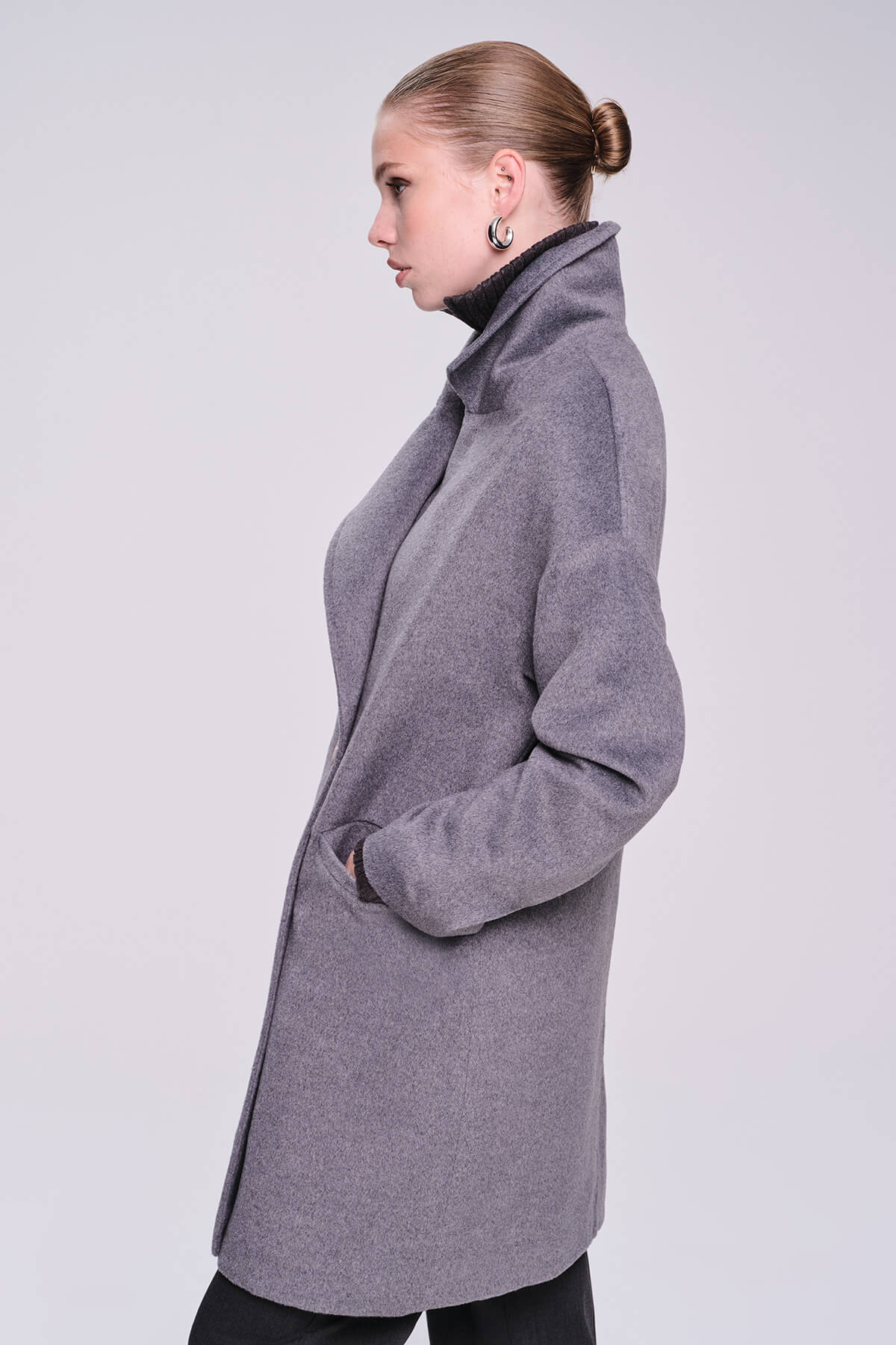A sleek, mid-length gray wool coat with a high collar and subtle texture.