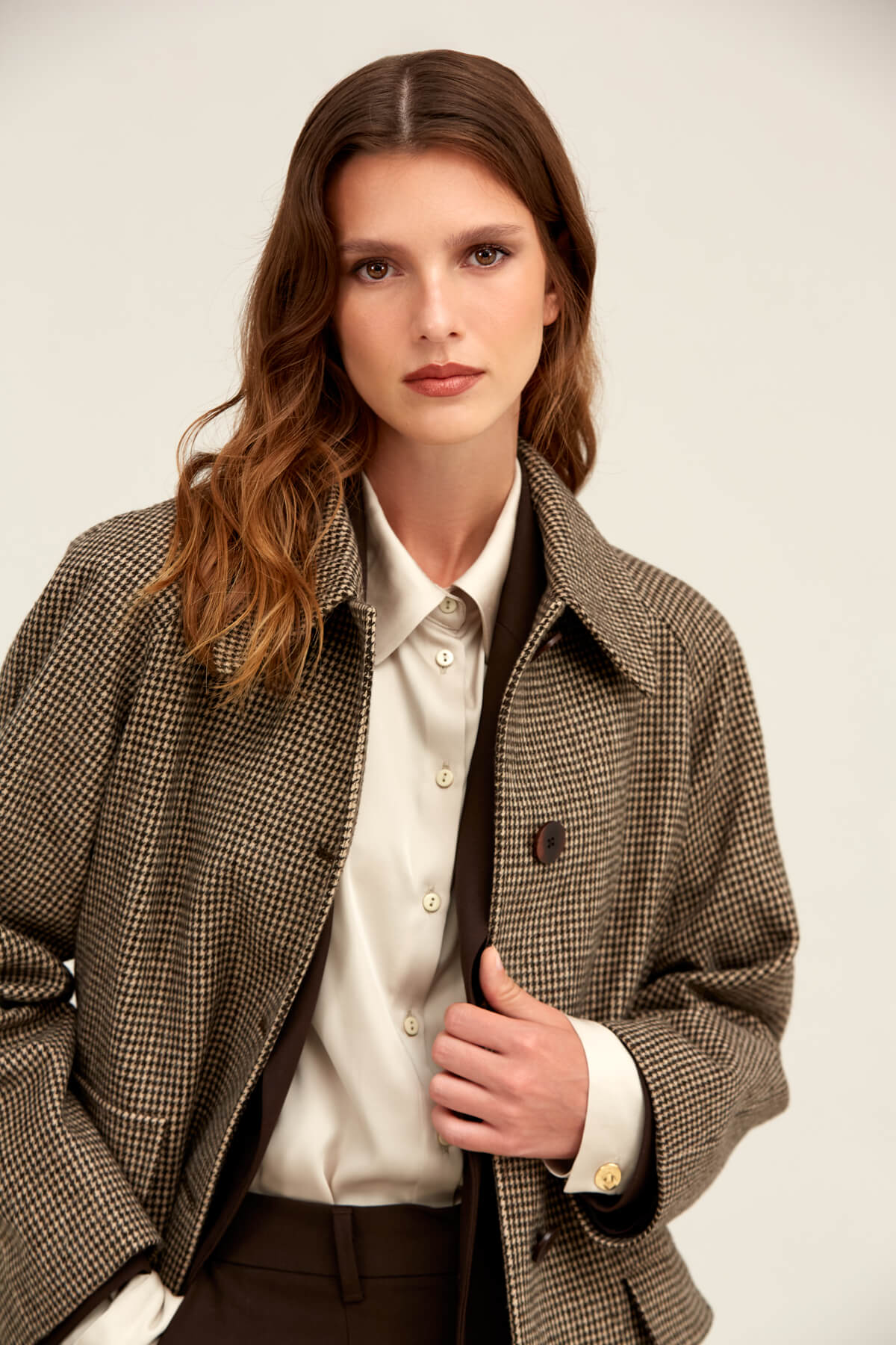Brown houndstooth wool-blend trench coat with notched lapels and dark brown buttons.