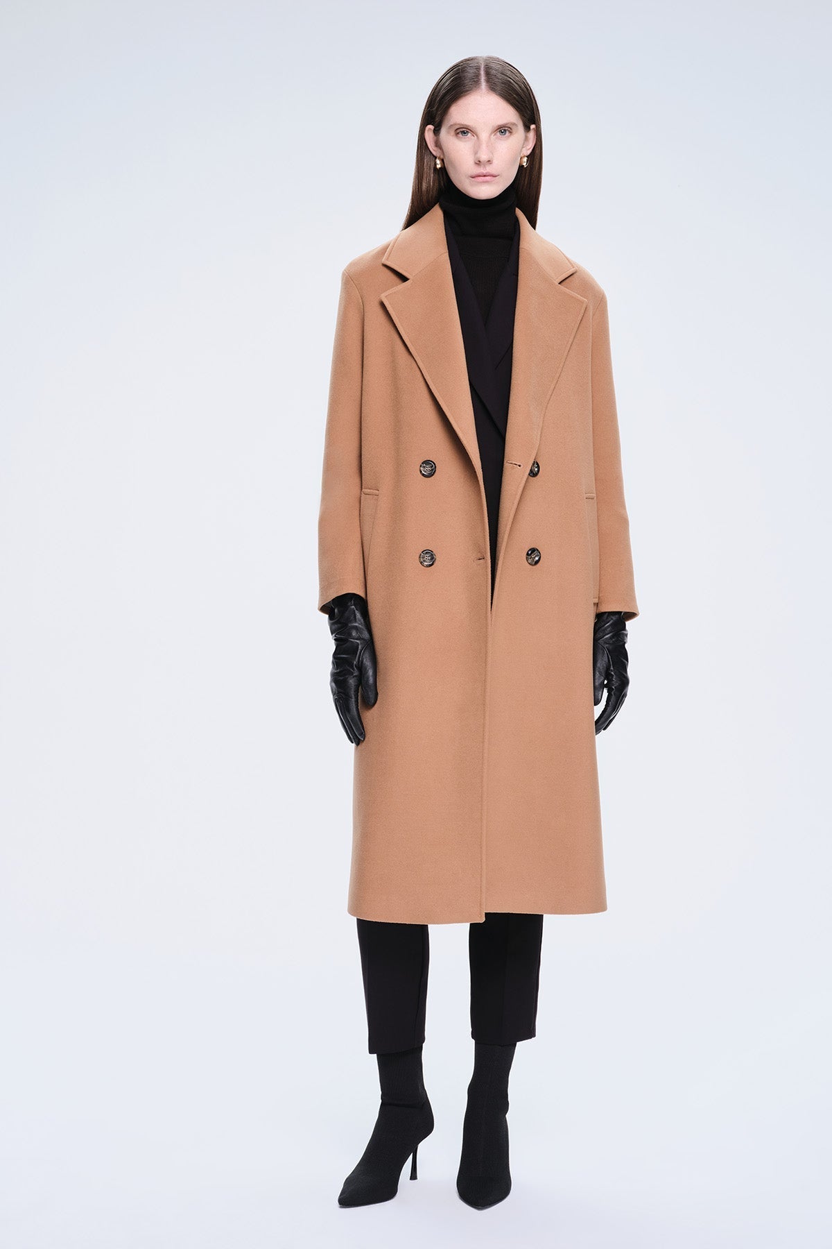 A camel-colored double-breasted wool coat with black buttons and a structured collar.