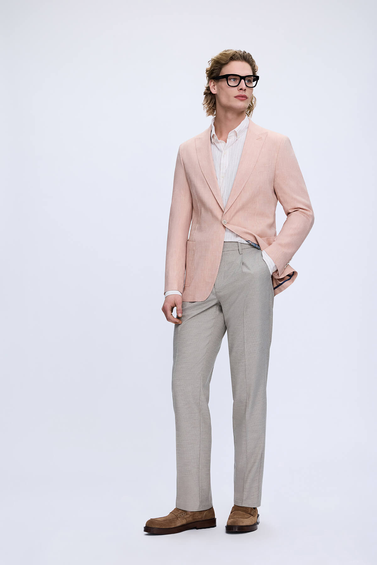 A man wearing a light pink blazer and beige trousers paired with dynamic fit gray linen blend jogger pants in a smart casual look