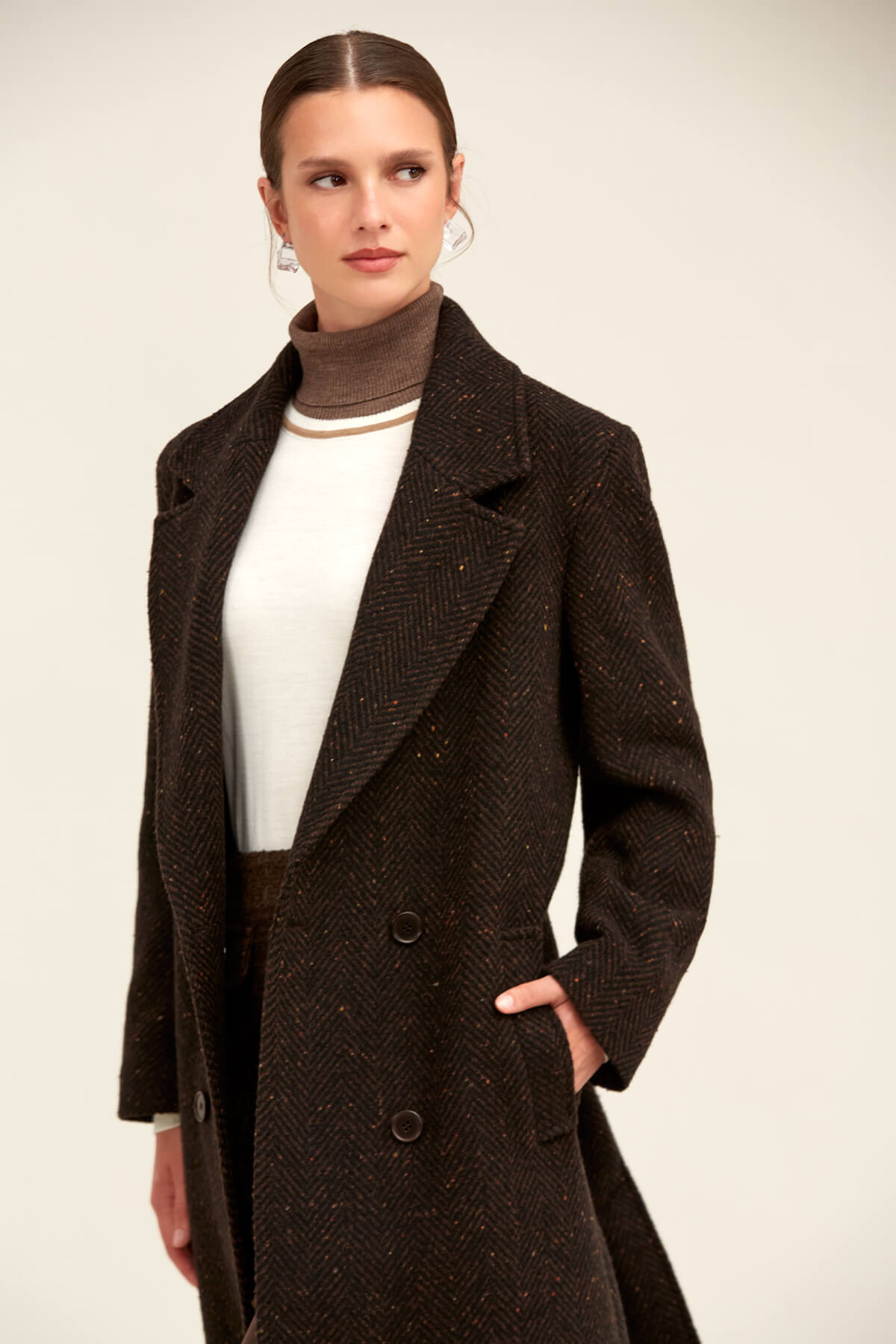 A dark brown herringbone wool coat with a classic double-breasted design and subtle speckled texture.