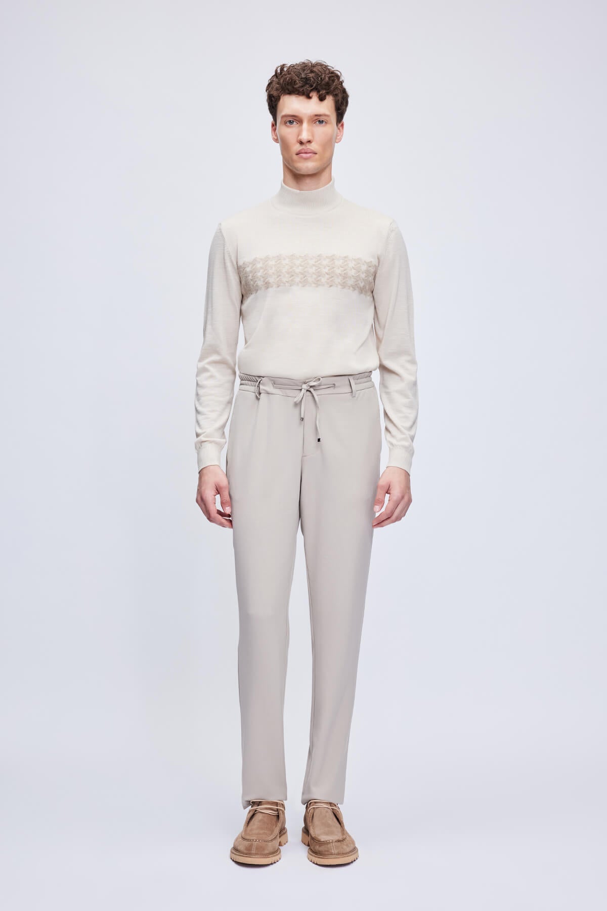 Beige turtleneck sweater with a subtle geometric pattern across the chest.