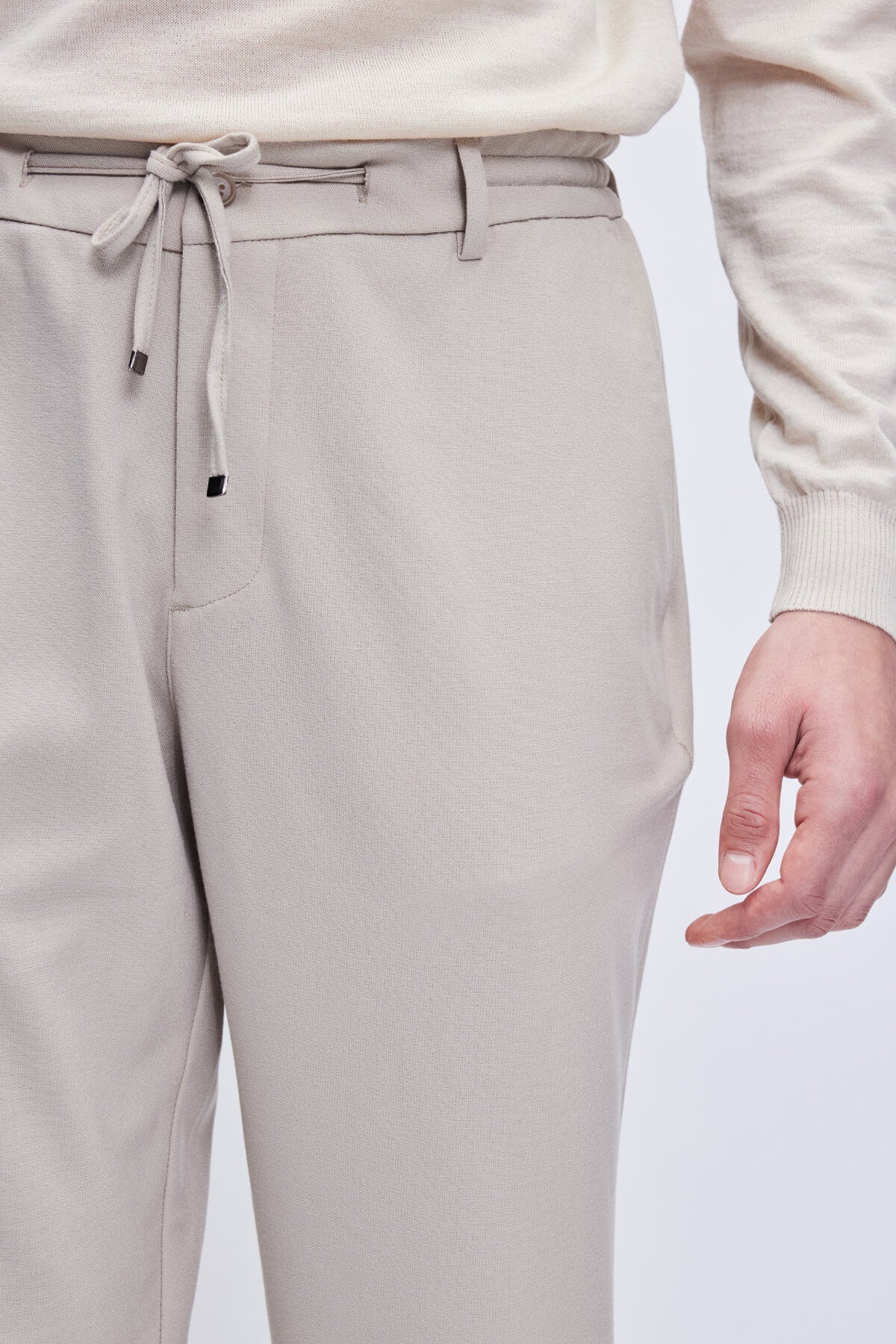 Beige drawstring trousers with a sleek, modern design and subtle texture.