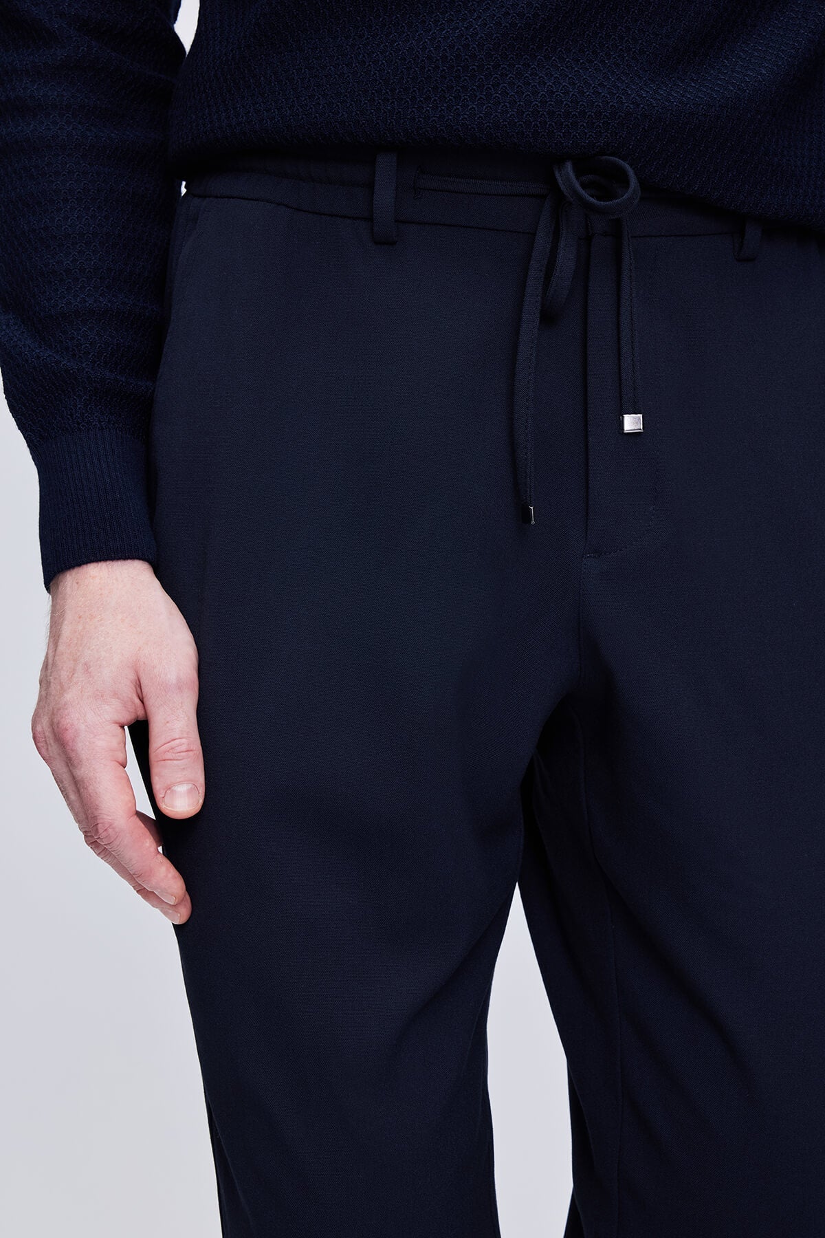 Dark navy blue drawstring trousers with a sleek, tailored fit and subtle texture.
