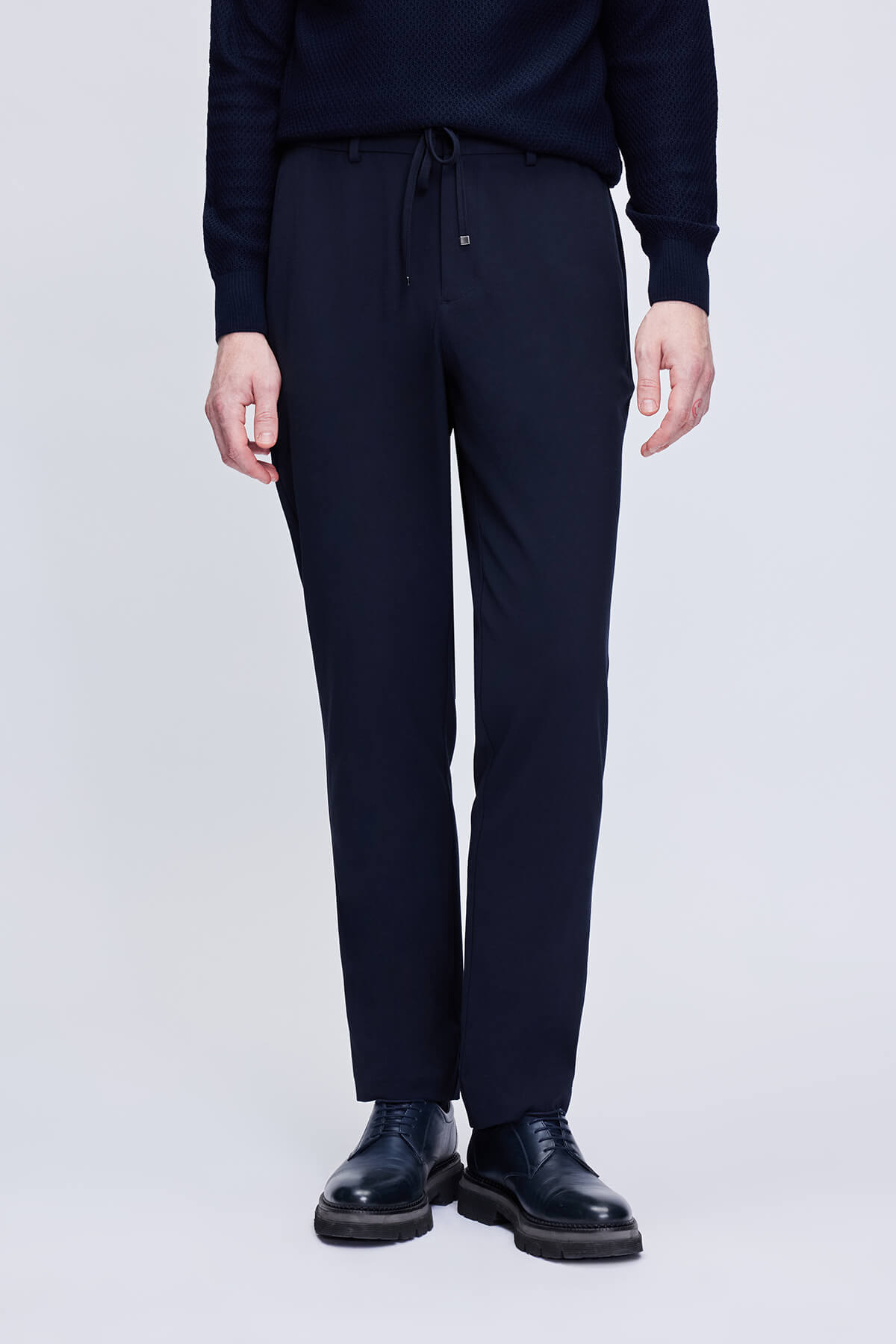 Dark navy wool blend trousers with a drawstring waistband and subtle brand logo on the left leg.