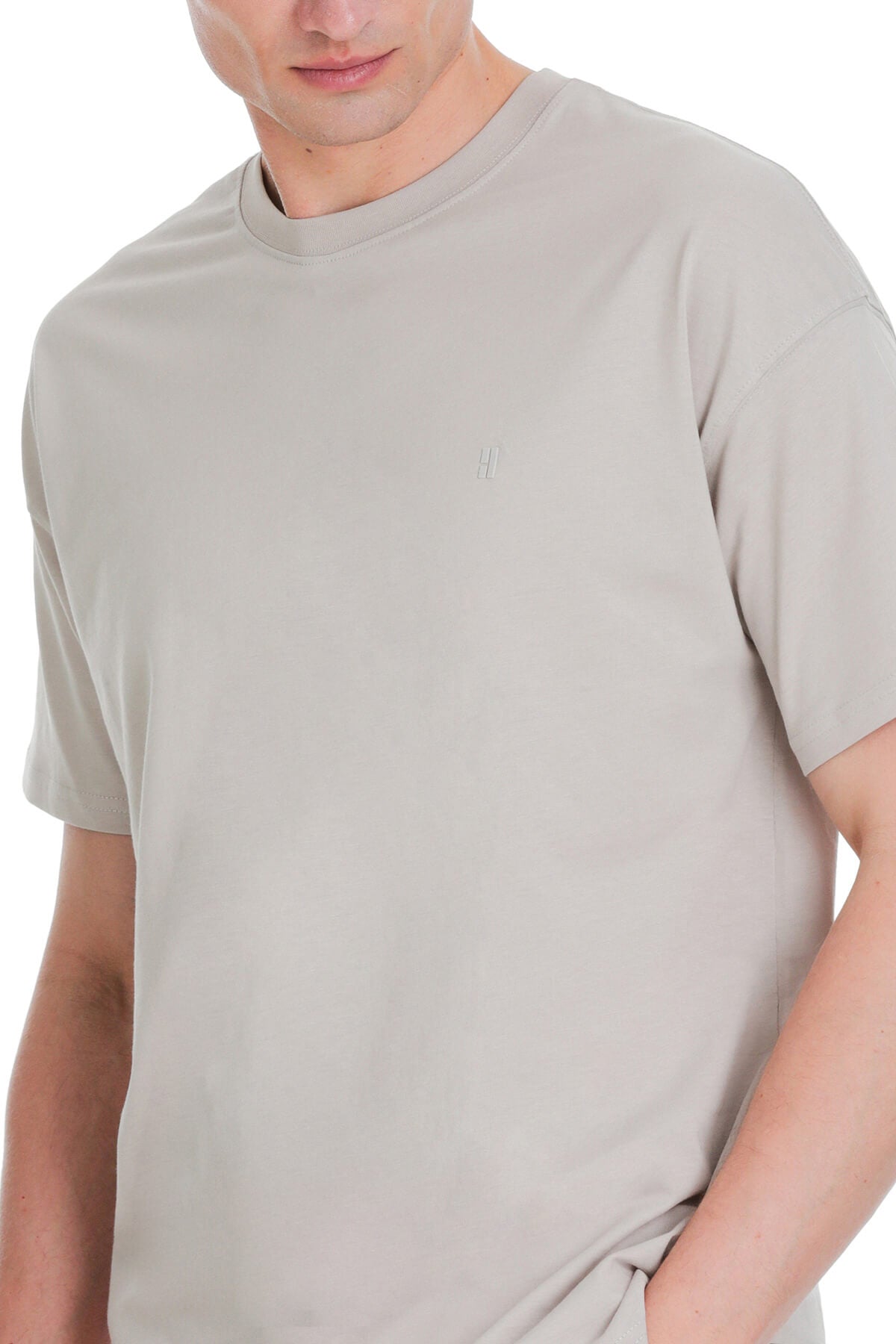 A minimalist gray ecru oversize crew neck t-shirt with a subtle embroidered logo on the left chest