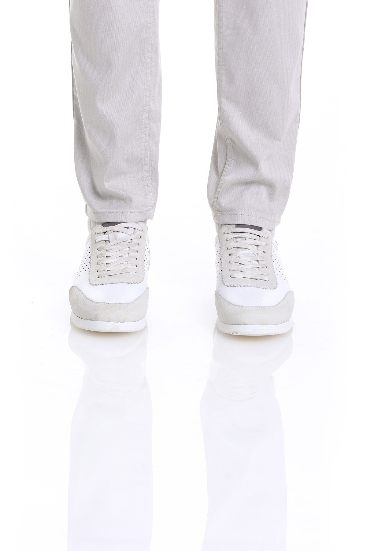 White and light gray athletic sneakers with perforated detailing on the upper.