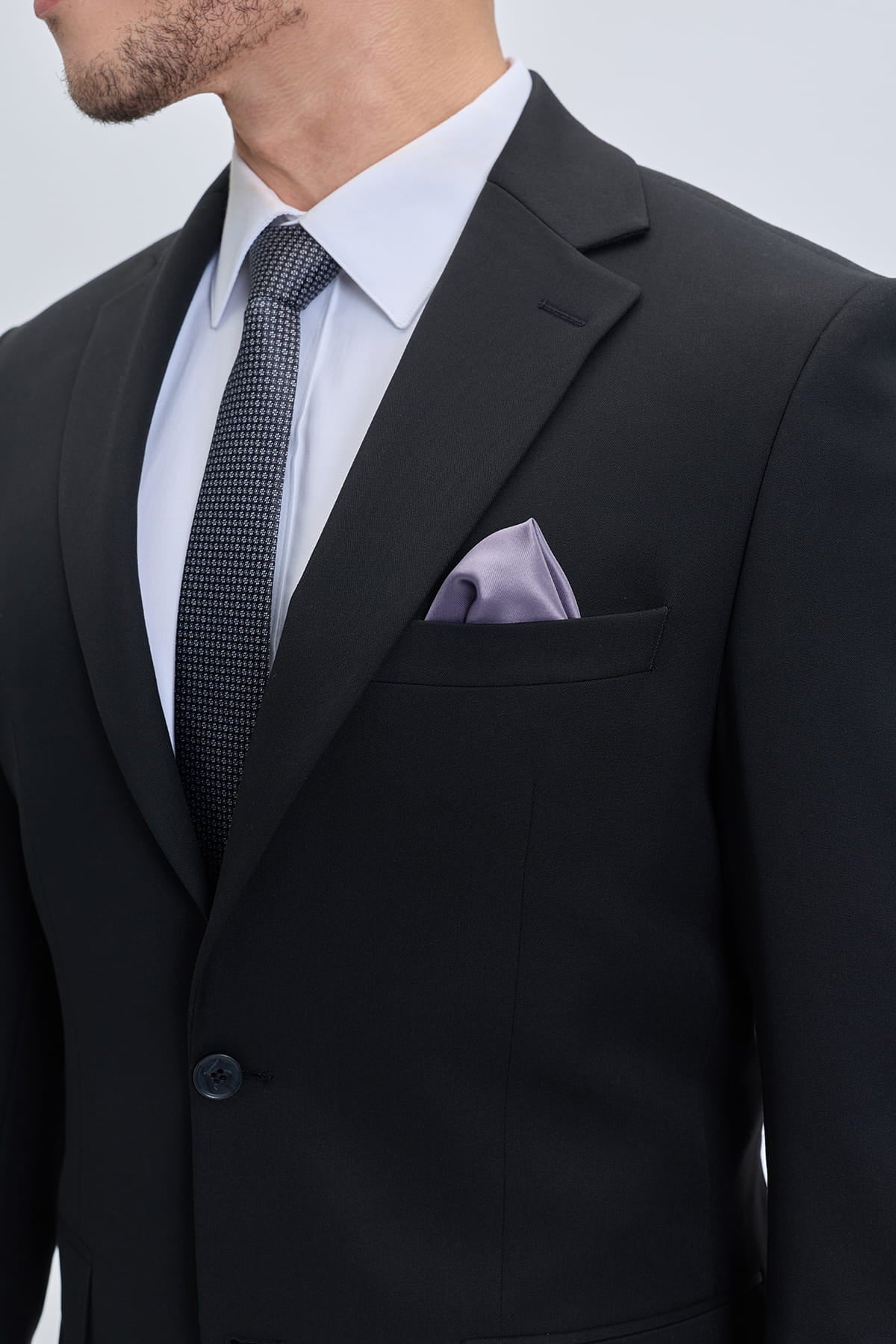 Muscle fit notch lapel black classic suit jacket with subtle sheen paired with white shirt and dark patterned tie
