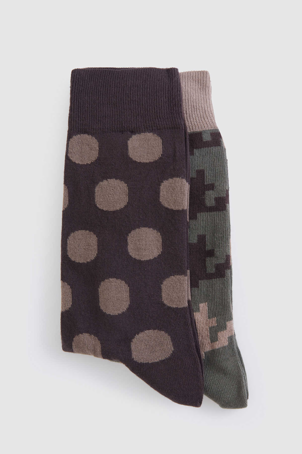 A pair of socks, one featuring a dark brown base with tan polka dots and the other displaying a pixelated camouflage pattern in shades of green and beige.