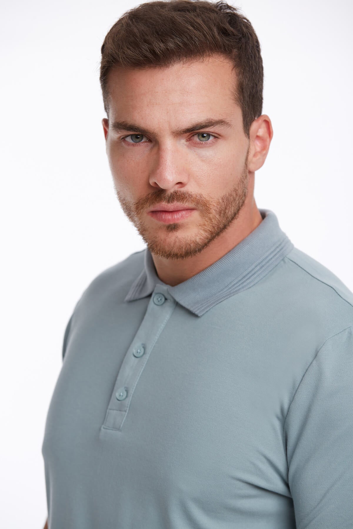 A man wearing a light blue, short-sleeved polo shirt with a classic collar and buttoned placket.