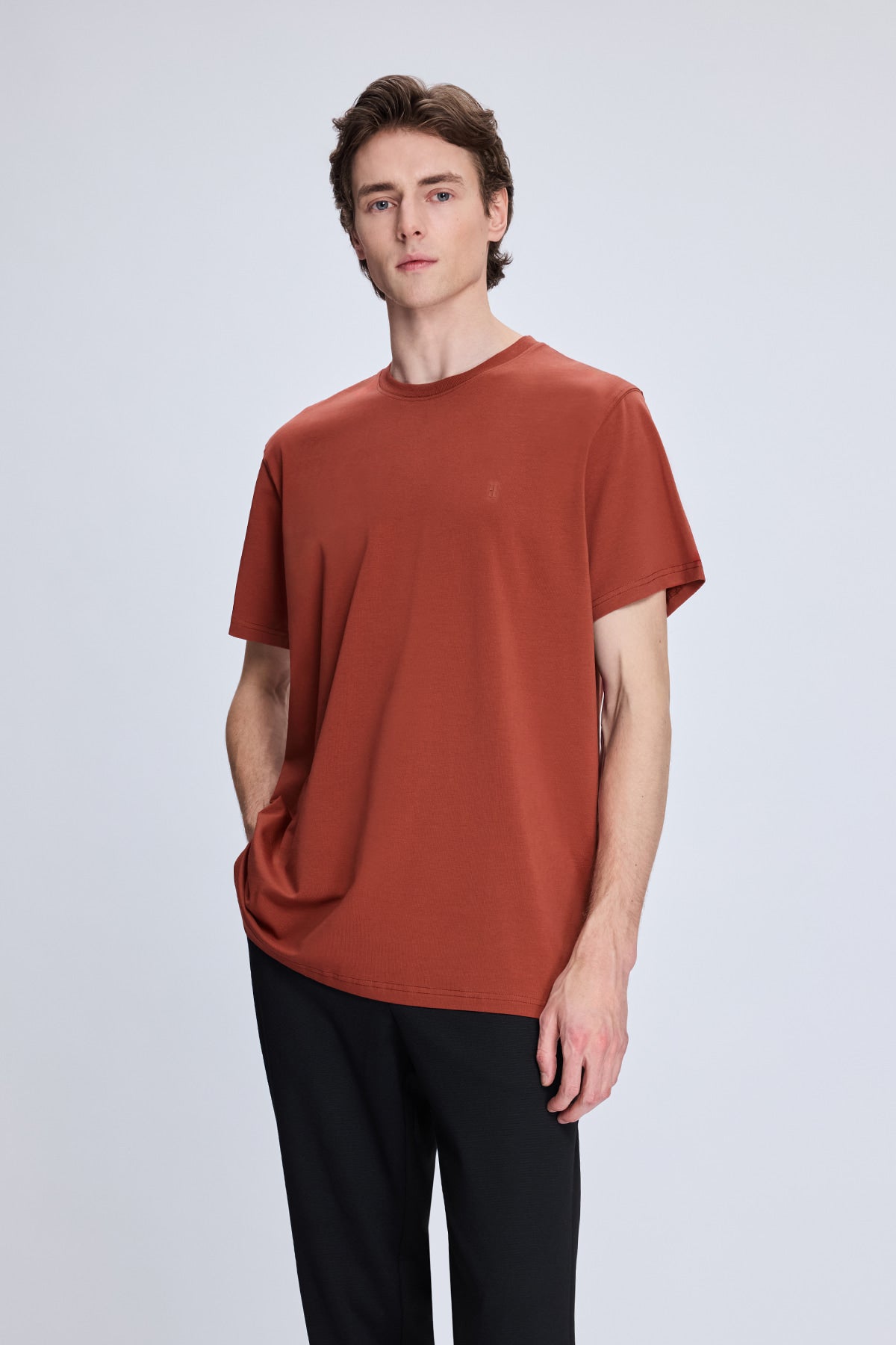 A rust-colored, short-sleeved cotton t-shirt with a simple crew neck and subtle stitching details.