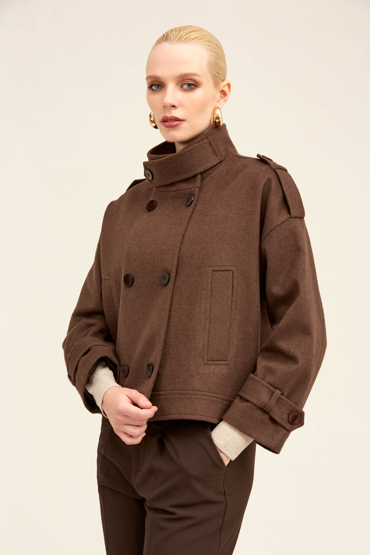 Brown woolen double-breasted coat with structured shoulders and belt-tied cuffs.