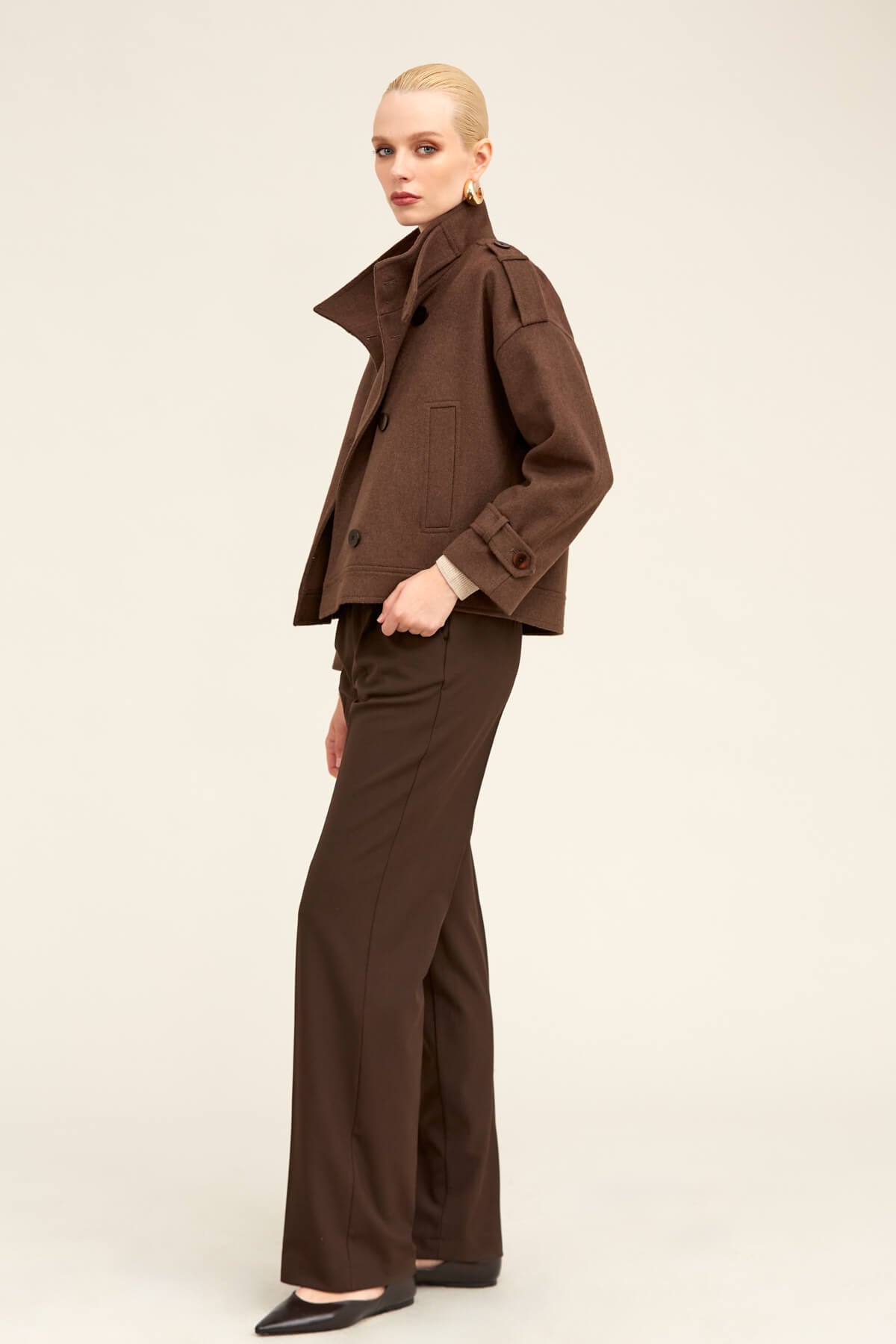 A sleek, chocolate-brown trench coat with a structured collar and flap pockets.