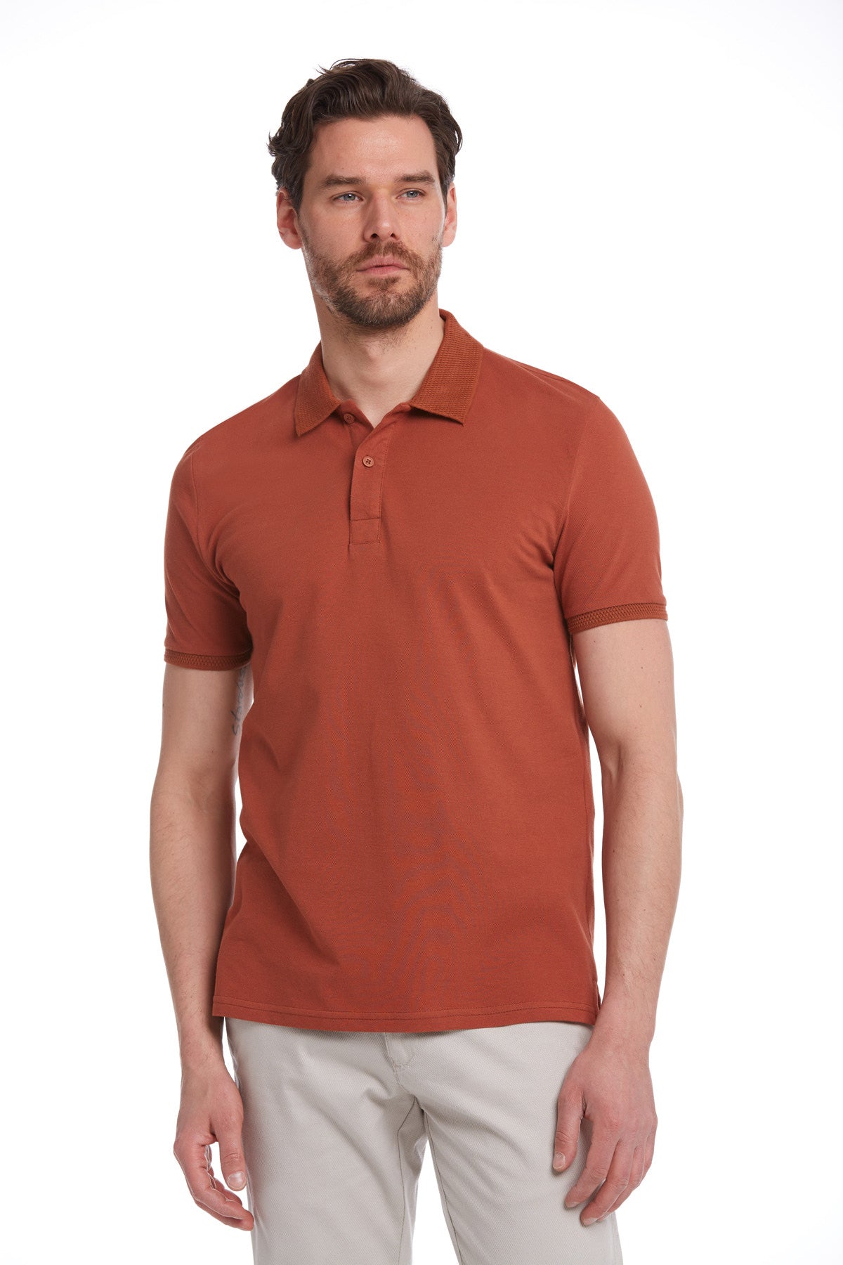 A man wearing a rust-colored, short-sleeved polo shirt with a classic collar and buttoned placket.