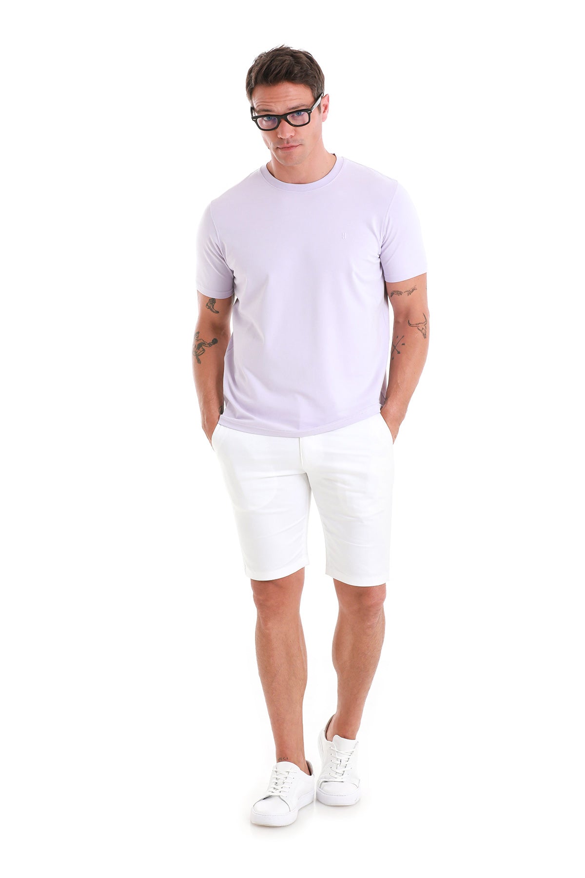 A man wearing a light lavender short-sleeved t-shirt and white shorts.