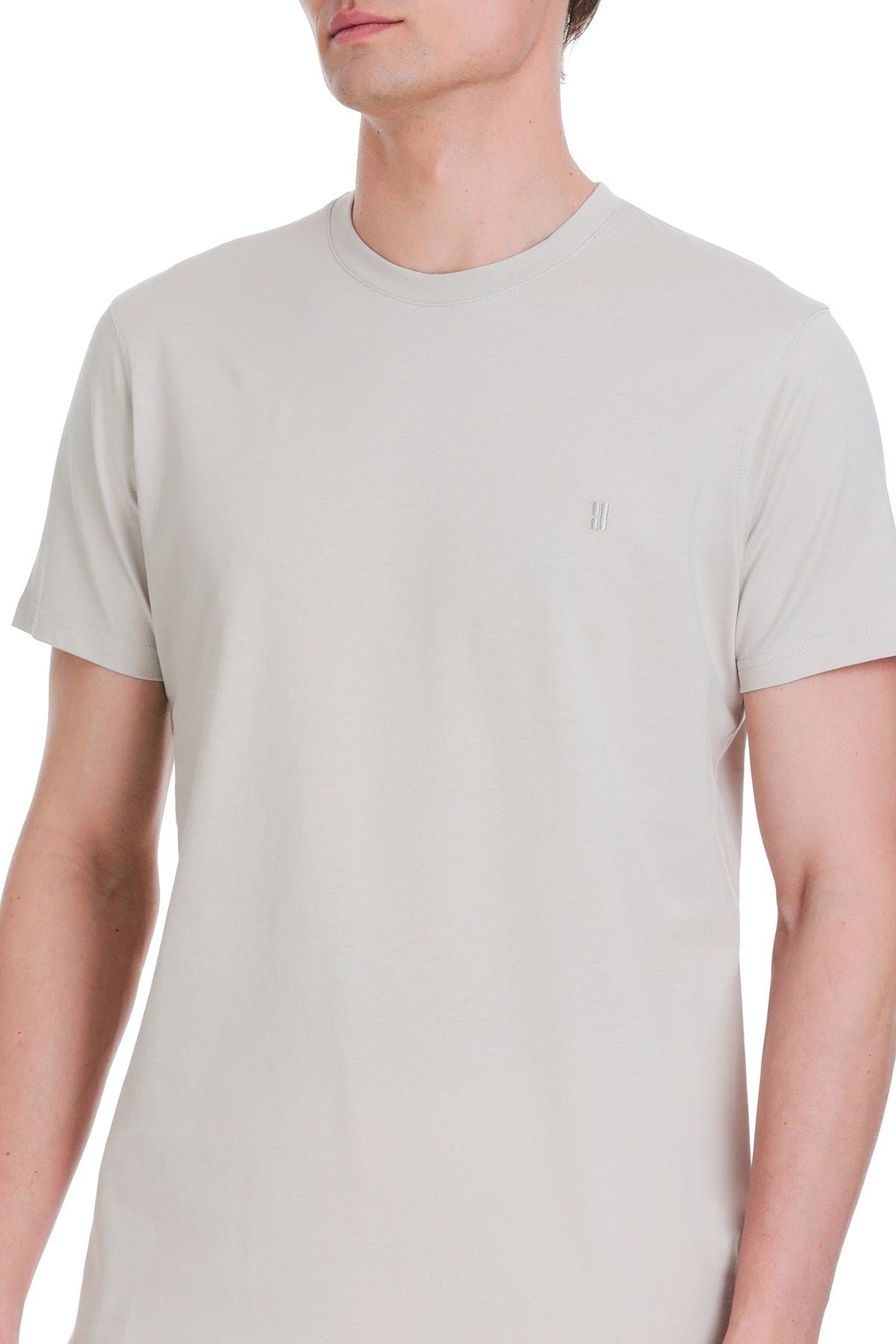 A minimalist off-white crew-neck t-shirt with a small embroidered logo on the left chest.