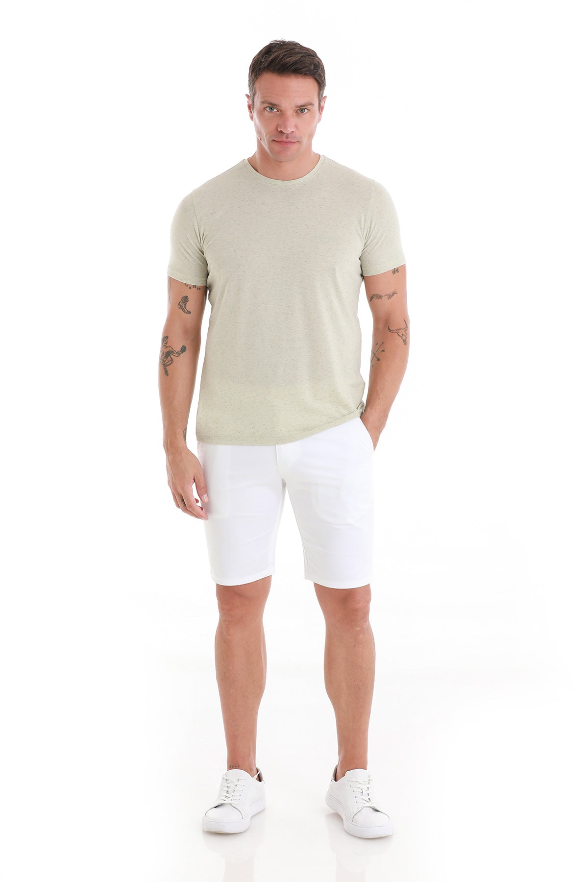 A man wearing a light green short-sleeved t-shirt and white shorts.