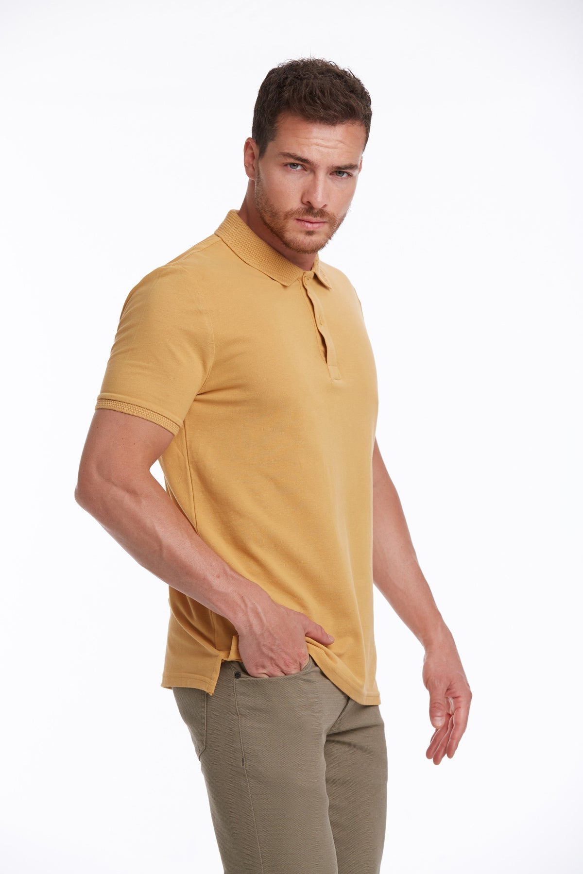 A man wearing a mustard-yellow short-sleeved polo shirt with a classic collar and ribbed cuffs.