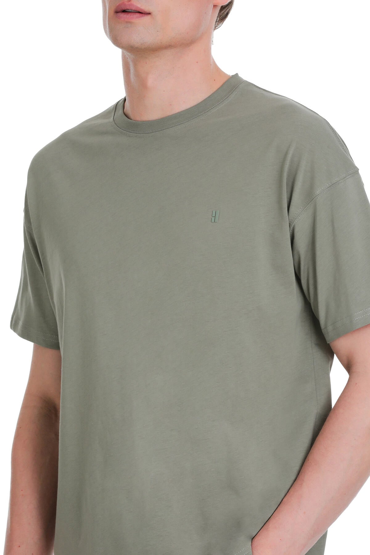 Olive green cotton crewneck t-shirt with a small embroidered logo on the left chest in a sage green oversize style