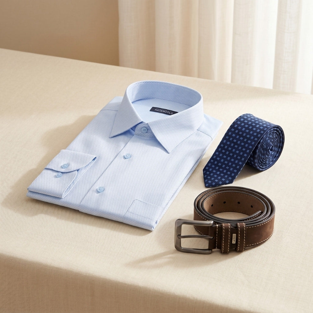 Light blue dress shirt with a brown belt and blue tie on a beige surface.