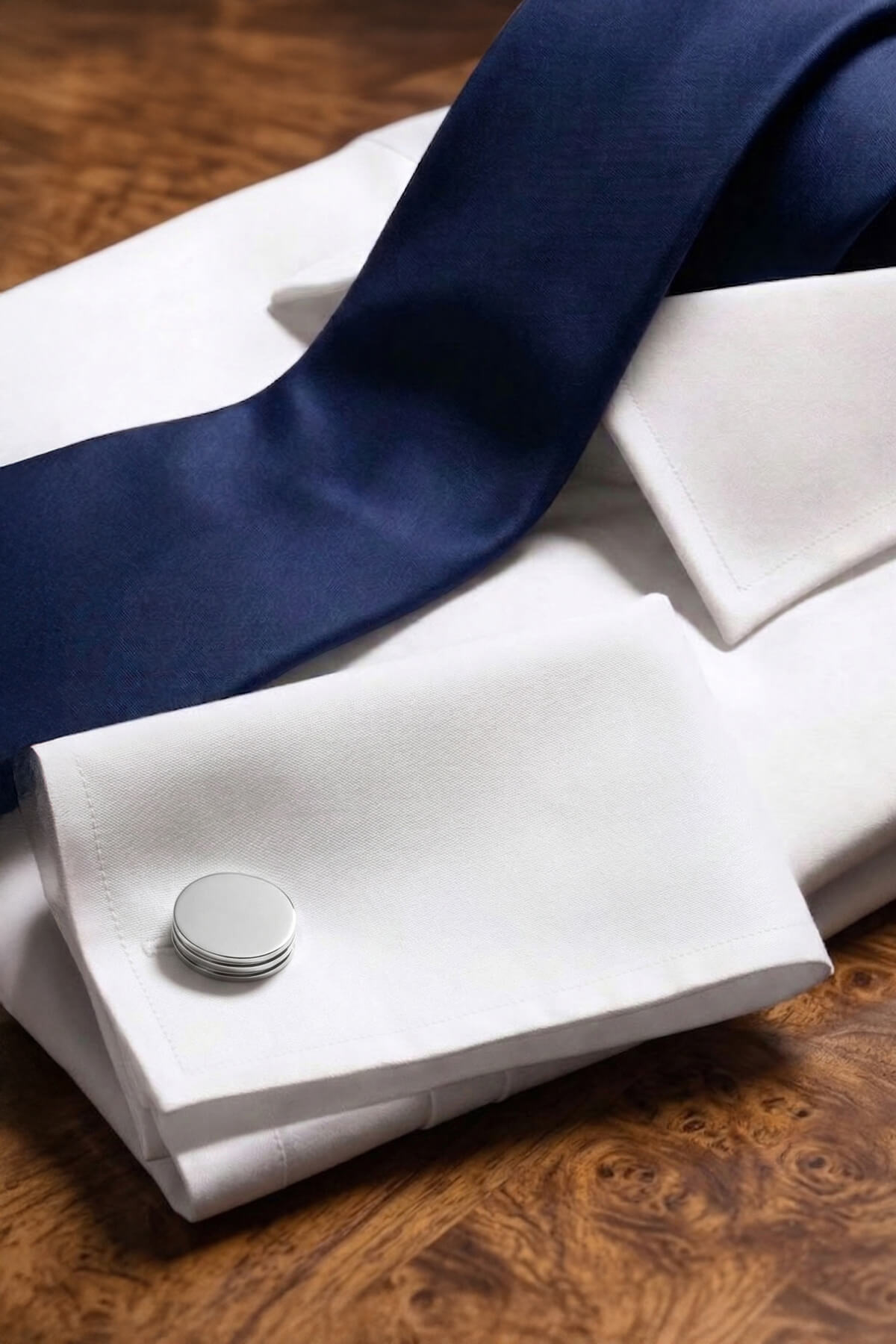 A sleek silver toned natural stone round cufflink with stacked circular design on a formal white shirt sleeve