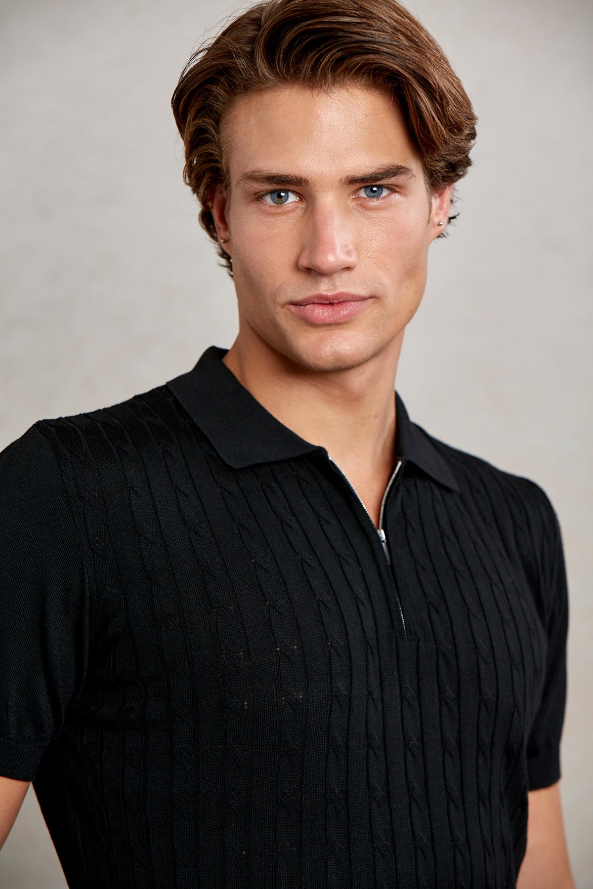 Black short-sleeved polo shirt with a ribbed knit texture and a zipper detail at the collar.