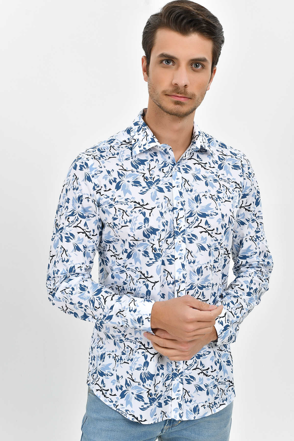 A man wearing a white long-sleeved button-up shirt with a blue and black floral pattern.