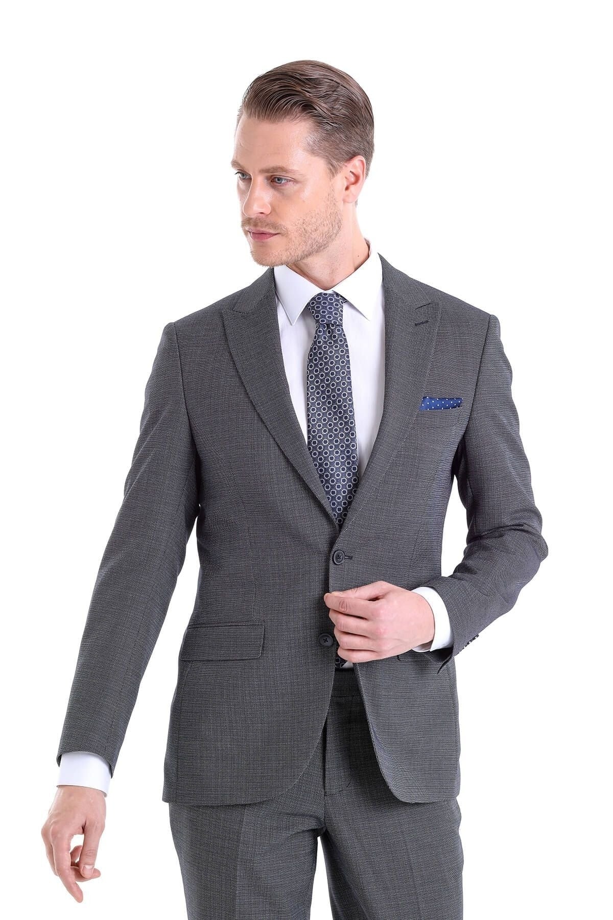 A sharply tailored charcoal gray suit with a subtle herringbone weave, featuring a matching pair of trousers and a crisp white dress shirt.