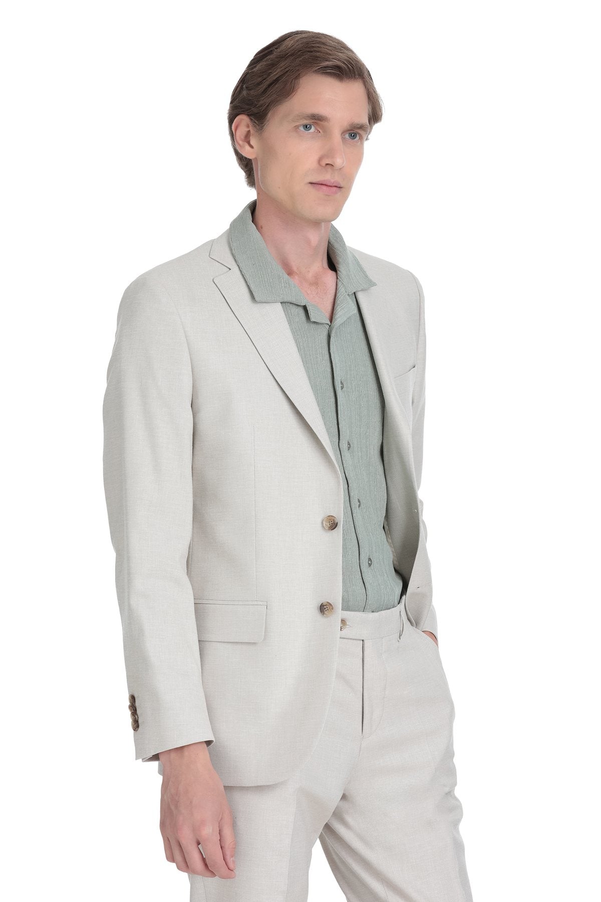 A man wearing a light gray blazer with matching trousers and a pale green button-up shirt underneath.