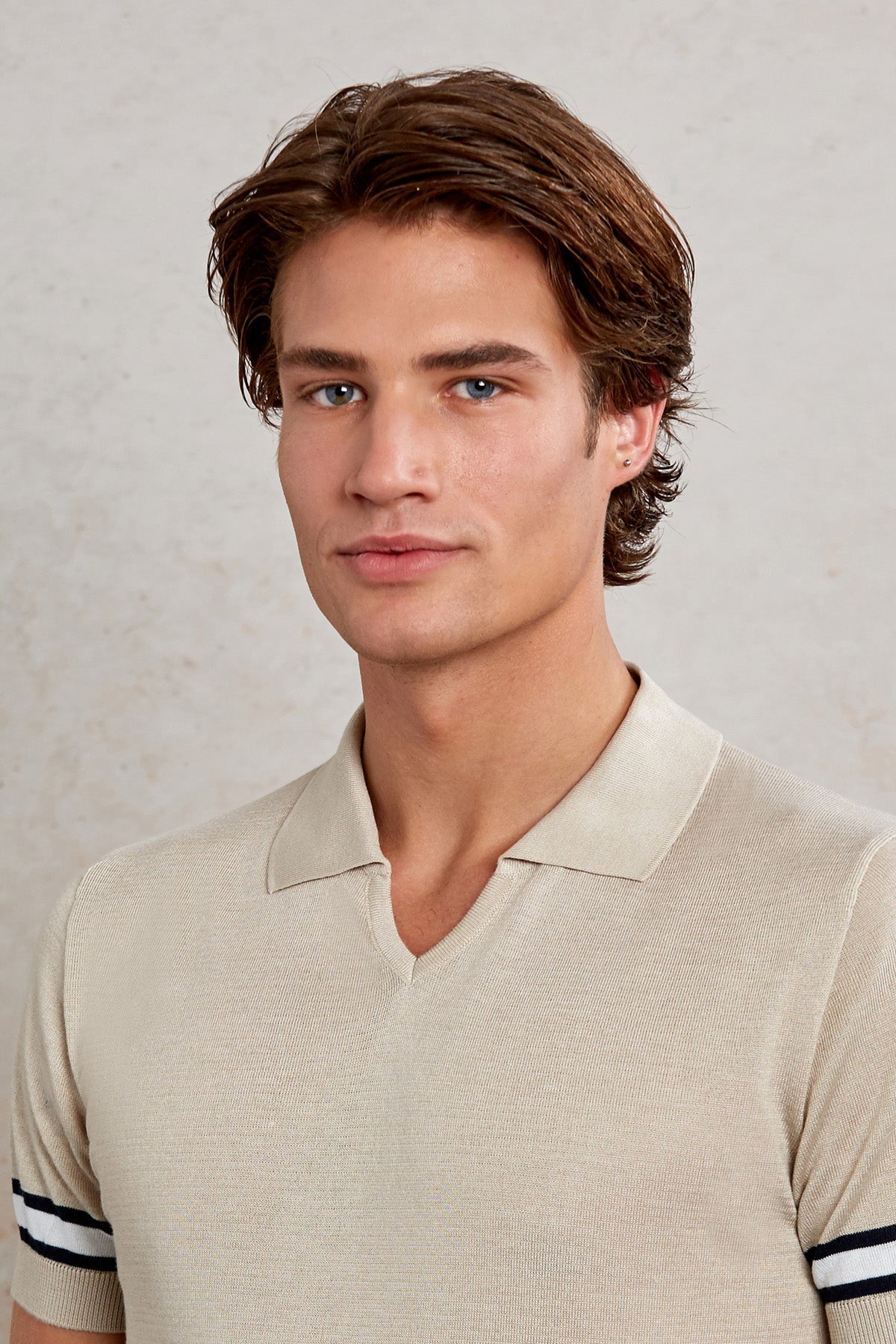 Beige textured knit polo shirt with black and white striped cuffs.