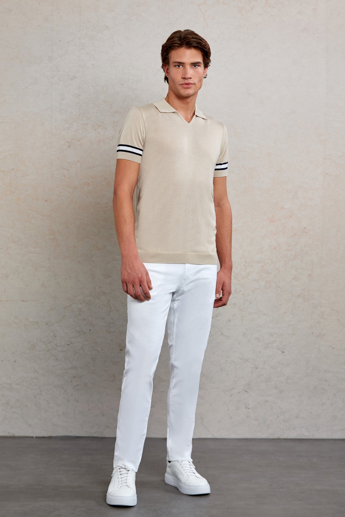 Beige polo shirt with black and white striped cuffs.