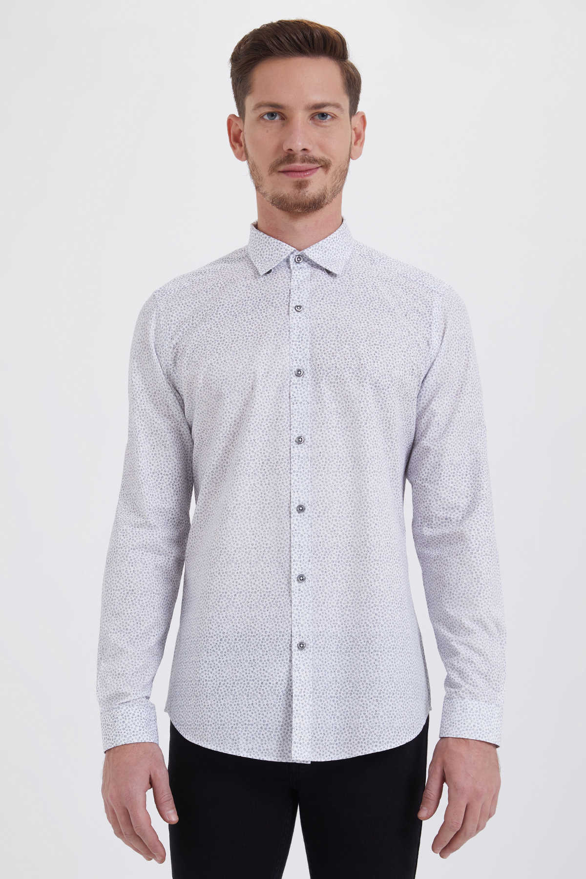 A man wearing a light gray button-down shirt with a subtle white geometric pattern.