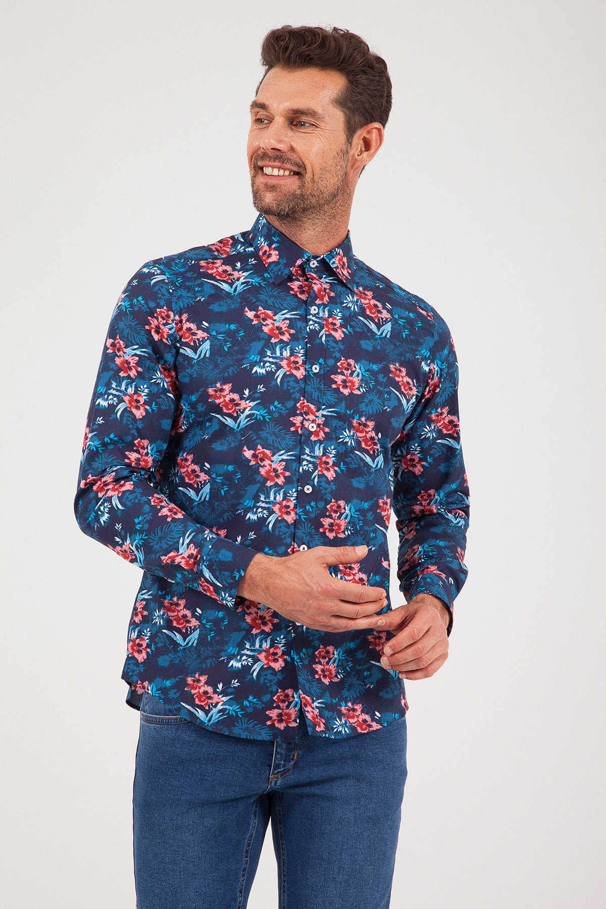 Men’s long-sleeved button-up shirt with a vibrant floral pattern in shades of red, pink, and teal on a dark navy background.